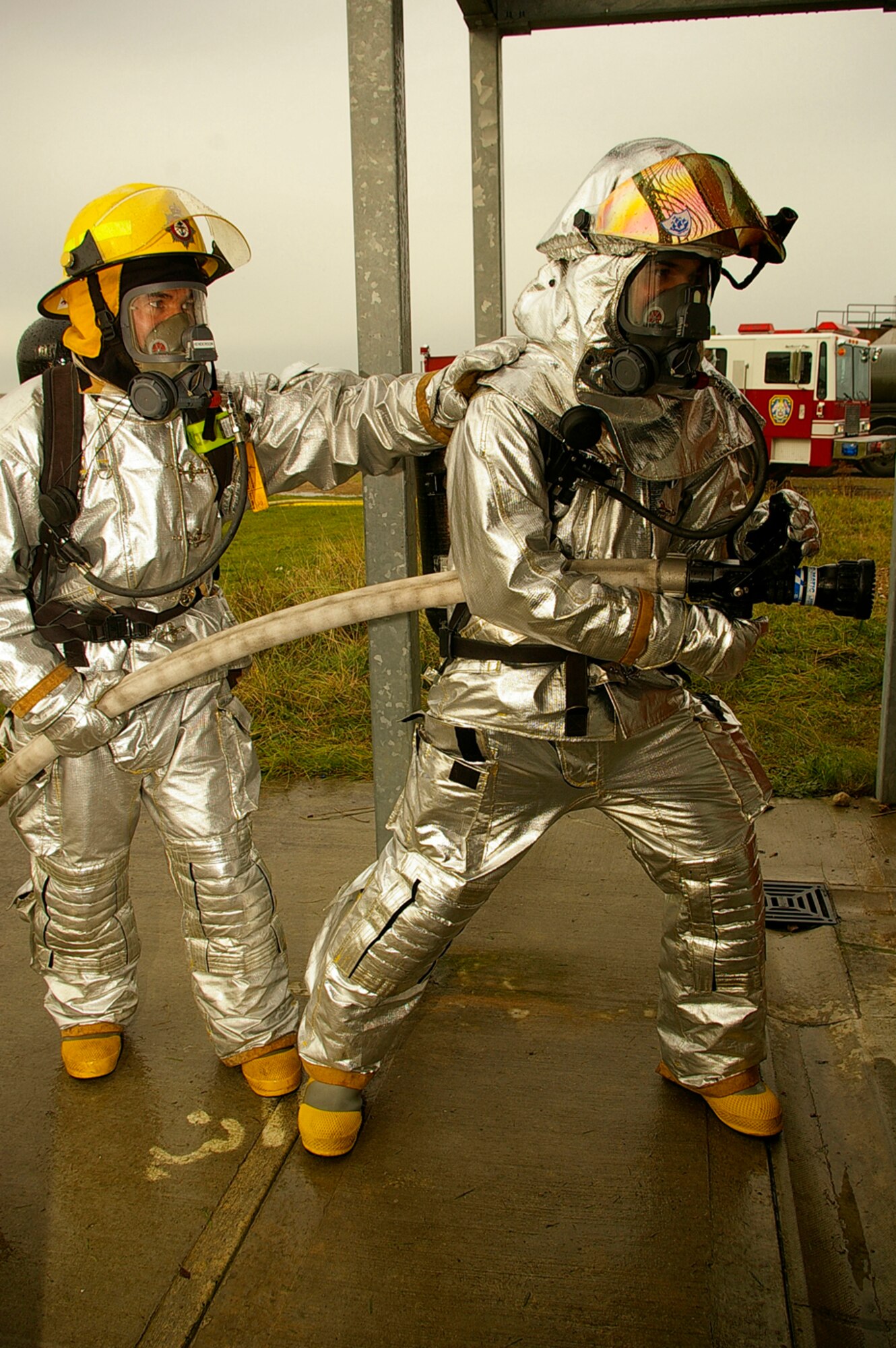 Gethin Jones, right, presenter of classic children's television programme, Blue Peter, with the help of Tech. Sgt. Rick Henderson, 100th Civil Engineer Fire Department, prepares to enter the smoke-house and put out a fire Oct. 1. The presenter and a camera crew visited the RAF Mildenhall Fire Department Oct. 1 and 2. Gethin spent two days with U.S. Air Force and Ministry of Defence firefighters, being trained by, and working alongside his firefighter buddy, Sergeant Henderson, when he and a camera crew came to record Gethin's two days as a firefighter for a special item on an upcoming edition of Blue Peter. The presenter worked with Green Watch and Blue Watch MoD firefighters, and U.S. military firefighters. He was put through his paces when he performed tasks such as a hose pull, mannequin drag, cutting up cars, and putting out fires on a simulated aircraft -- all while wearing a protective clothing and equipment weighing between 70 to 100 pounds. (U.S. Air Force photo by Karen Abeyasekere)