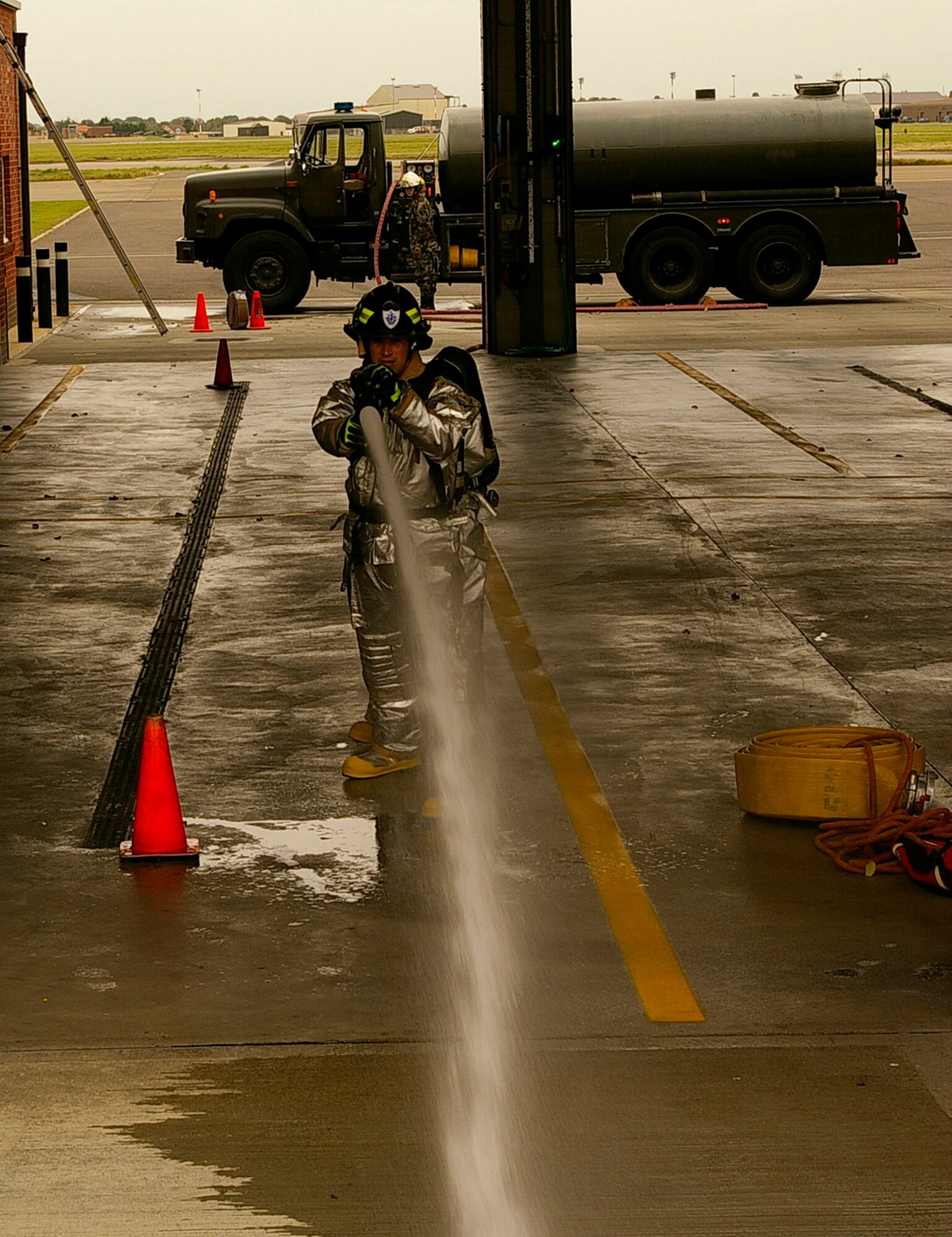 After completing a hose pull and variety of firefighter challenges, Gethin Jones, children's TV presenter from "Blue Peter," opens the hose and aims it before hitting the target. The presenter spent two days with Ministry of Defence and U.S. Air Force firefighters at RAF Mildenhall, and joined them in training exercises including cutting up cars, putting out fires in the smoke house and on the simulated aircraft. (U.S. Air Force photo by Karen Abeyasekere)