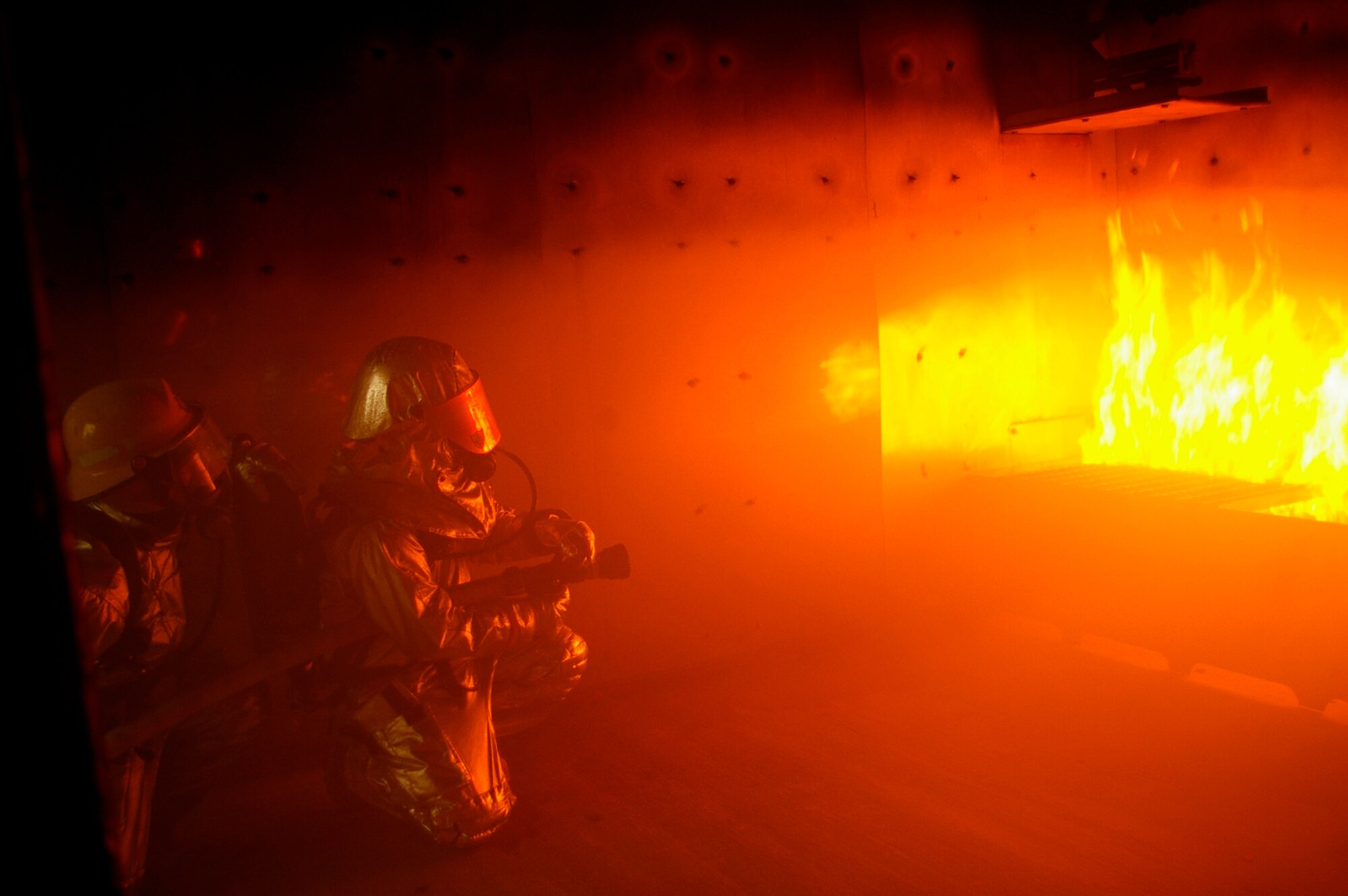 Gethin Jones, right, presenter of classic children's television programme, Blue Peter, helps Tech. Sgt. Rick Henderson, 100th Civil Engineer Fire Department, put out a fire in the smoke-house at RAF Mildenhall Oct. 1. The presenter and a camera crew visited the RAF Mildenhall Fire Department Oct. 1 and 2. Gethin spent two days with U.S. Air Force and Ministry of Defence firefighters, being trained by, and working alongside his firefighter buddy, Sergeant Henderson, when he and a camera crew came to record Gethin's two days as a firefighter for a special item on an upcoming edition of Blue Peter. The presenter, who is currently starring in "Strictly Come Dancing," worked with Green Watch and Blue Watch MoD firefighters, and U.S. military firefighters. He was put through his paces when he performed tasks such as a hose pull, mannequin drag, cutting up cars, and putting out fires on a simulated aircraft -- all while wearing a protective clothing and equipment weighing between 70 to 100 pounds. (U.S. Air Force photo by Karen Abeyasekere)