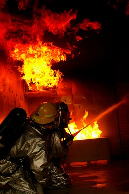 Gethin Jones, right, presenter of classic children's television programme, Blue Peter, helps Tech. Sgt. Rick Henderson, 100th Civil Engineer Fire Department, put out a fire in the smoke-house at RAF Mildenhall Oct. 1. The presenter and a camera crew visited the RAF Mildenhall Fire Department Oct. 1 and 2. Gethin spent two days with U.S. Air Force and Ministry of Defence firefighters, being trained by, and working alongside his firefighter buddy, Sergeant Henderson, when he and a camera crew came to record Gethin's two days as a firefighter for a special item on an upcoming edition of Blue Peter. The presenter, who is currently starring in "Strictly Come Dancing," worked with Green Watch and Blue Watch MoD firefighters, and U.S. military firefighters. He was put through his paces when he performed tasks such as a hose pull, mannequin drag, cutting up cars, and putting out fires on a simulated aircraft -- all while wearing a protective clothing and equipment weighing between 70 to 100 pounds. (U.S. Air Force photo by Karen Abeyasekere)