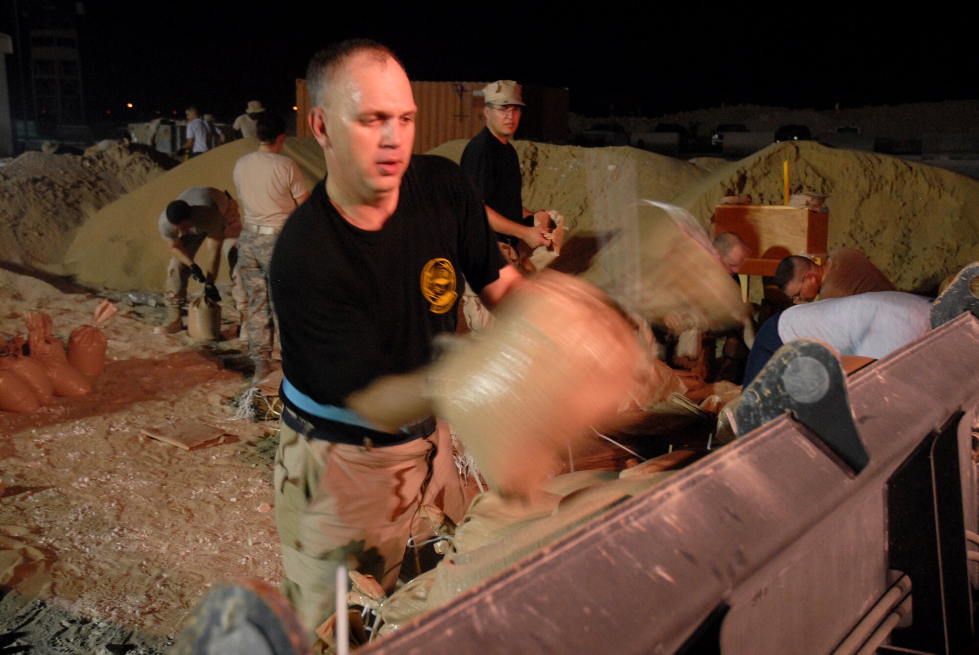 Master Sgt. Kenneth Curtis, 379th Expeditionary Civil Engineer Squadron, places a sandbag into a backhoe bucket during a bunker building project Oct. 2. Sergeant Curtis is deployed from the 509th CES at Whiteman Air Force Base, to Southwest Asia. (U.S. Air Force photo/Staff Sgt. Douglas Olsen)