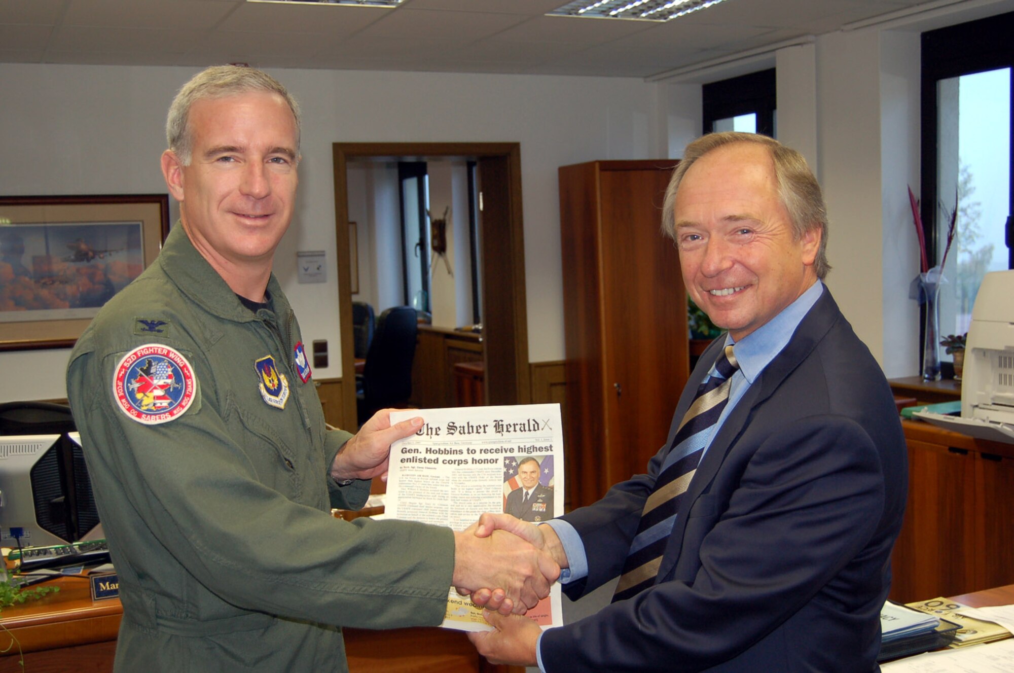 SPANGDAHLEM AIR BASE, Germany – Col. Thomas Feldhausen, 52nd Fighter Wing vice commander, thanks John Thompson, The Saber Herald publisher, for his work to bring a newspaper back to Spangdahlem Air Base Oct. 5. The Saber Herald is published by AdvantiPro, who consolidates information from Spangdahlem Air Base and other Air Force Web pages into the paper. (U.S. Air Force photo/Capt. Kevin Coffman)