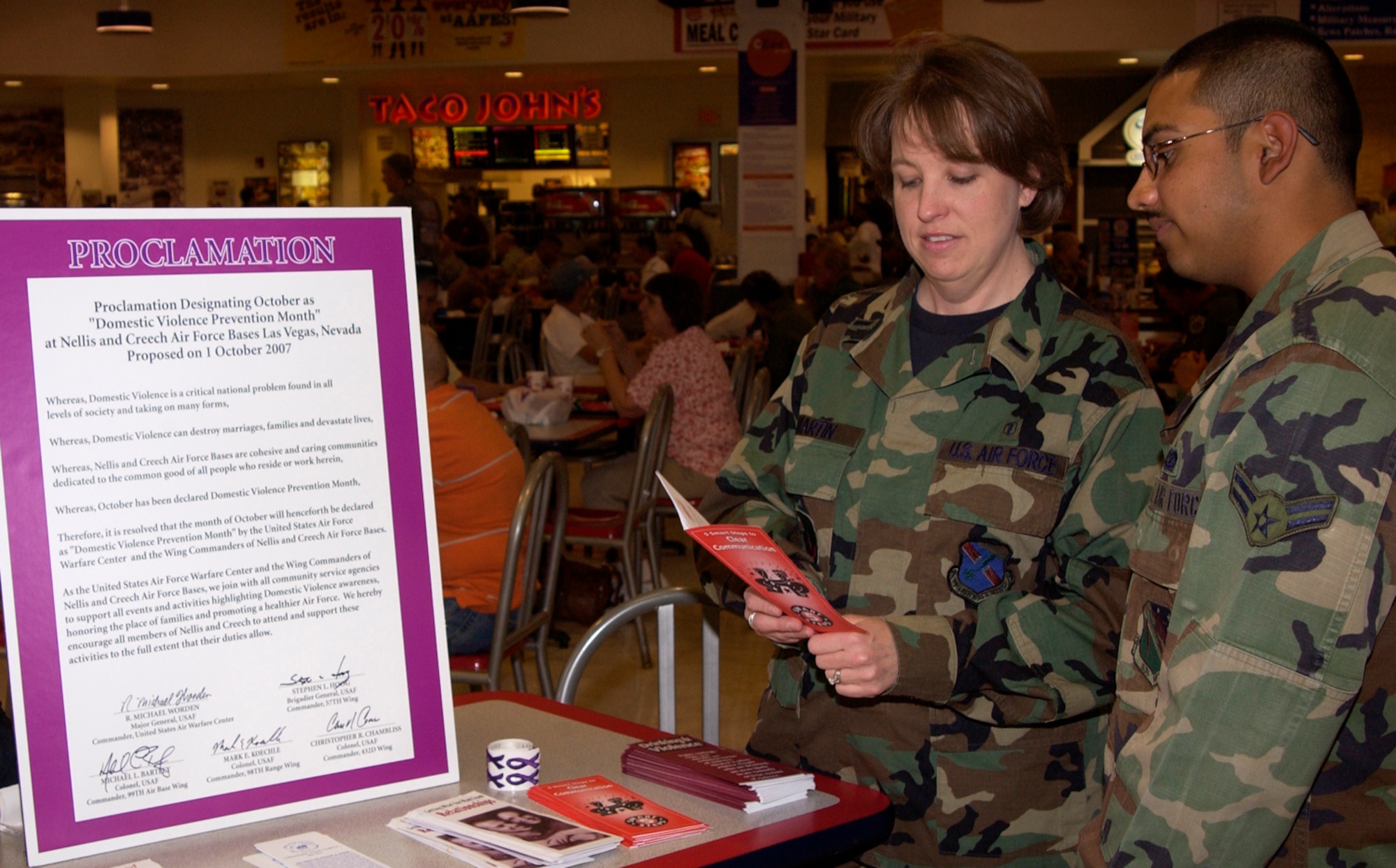 1st Lt. Jennifer Martin, a clinical social worker with the 99th Medical Operations Squadron family advocacy program, educates Airman 1st Class Edward Prince, client support administrator with the HH-60 Combined Test Force, about domestic violence at the Domestic Violence Awareness display at the Nellis Base Exchange Oct. 10. Nellis and Creech Air Force bases have declared October Domestic Violence Prevention Month. One of the ways Family Advocacy is doing its part to educate the base population is by handing out purple ribbons at the BX every Wednesday and Friday from 11 a.m. to 12:30 p.m. throughout the month of October in memory of those lost to domestic violence. (U.S. Air Force photo by Airman 1st Class Oleksandra Manko)

