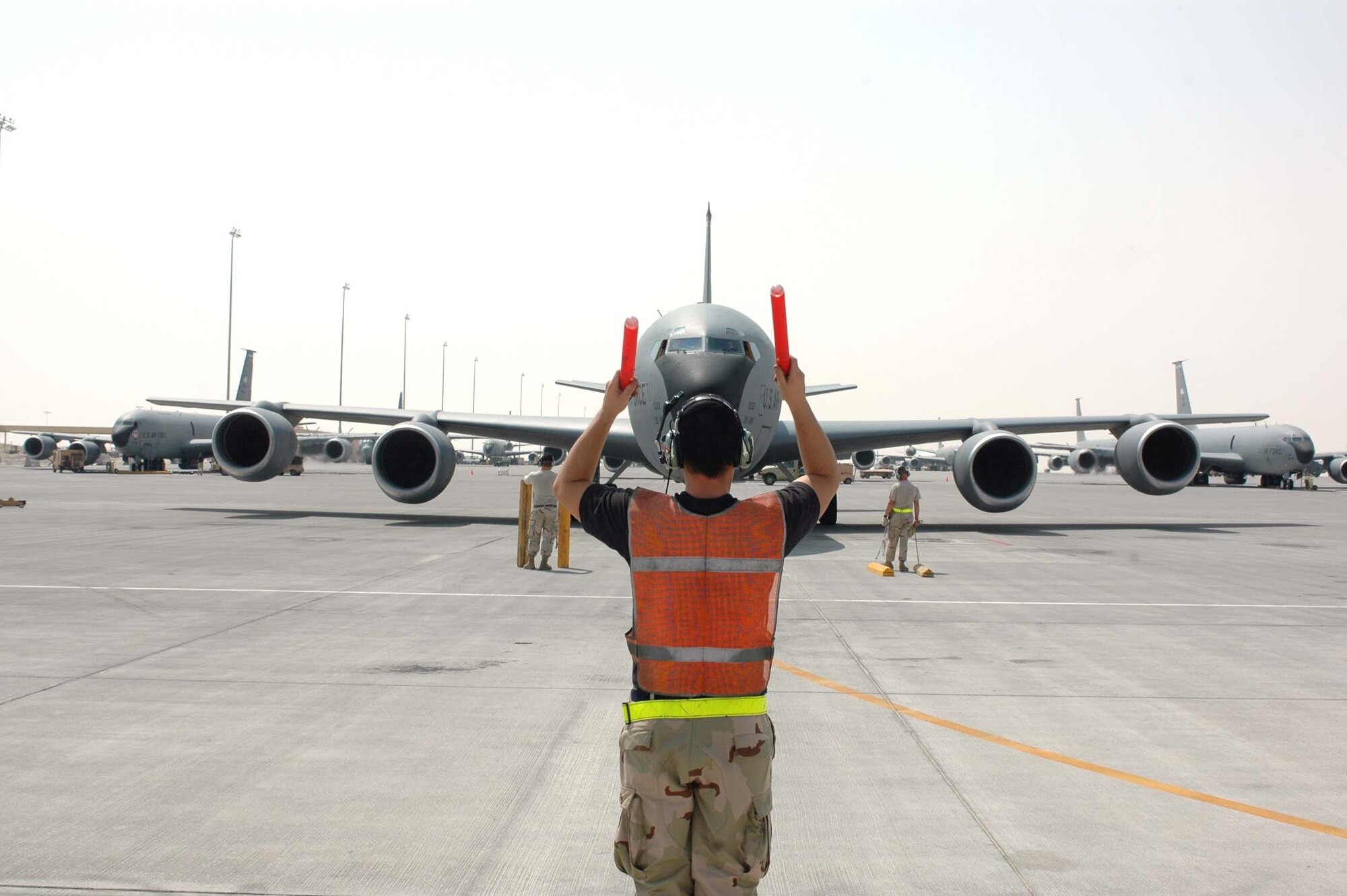Senior Airman Mike McGovern marshals a KC-135 Stratotanker to its parking spot with Tech. Sgt. Robert Wade (left) and Senior Airman Neal Sicard (right) standing by to place chocks around the aircraft's tires. The Airmen are assigned to the 340th Aircraft Maintenance Unit in Southwest Asia. (U.S. Air Force photo/Staff Sgt. Jason Barebo)