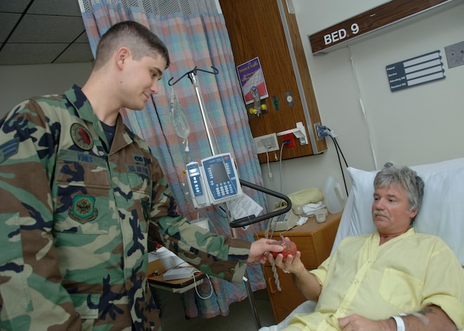 Senior Airman James Vines, 437th Airlift Wing Protocol protocol specialist, hands a decorated pumpkin to retired Army Sergeant 1st Class Darrell Kissinger at the Ralph H. Johnson VA Medical Center Wednesday. (U.S. Air Force photo/Airman 1st Class Katie Gieratz)