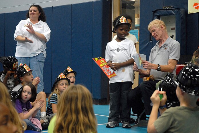 Christopher Shropshire, son of Master Sgt. Kendrick Shropshire, receives an award from Robert Hoffman, 437th Civil Engineer Squadron fire inspector, for his award-winning Fire Prevention Week essay at the Youth Programs Center Tuesday. (U.S. Air Force photo/Airman Melissa White)