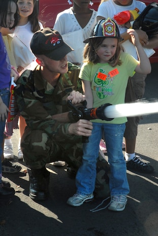 Staff Sgt. Darren Howe, 437th Civil Engineer Squadron firefighter, shows Isabel Briscoe, 5, daughter of Staff Sgt. Candice Kundle, how to spray the water hose from a fire truck at the Youth Programs Center Tuesday. (U.S. Air Force photo/Airman Melissa White)