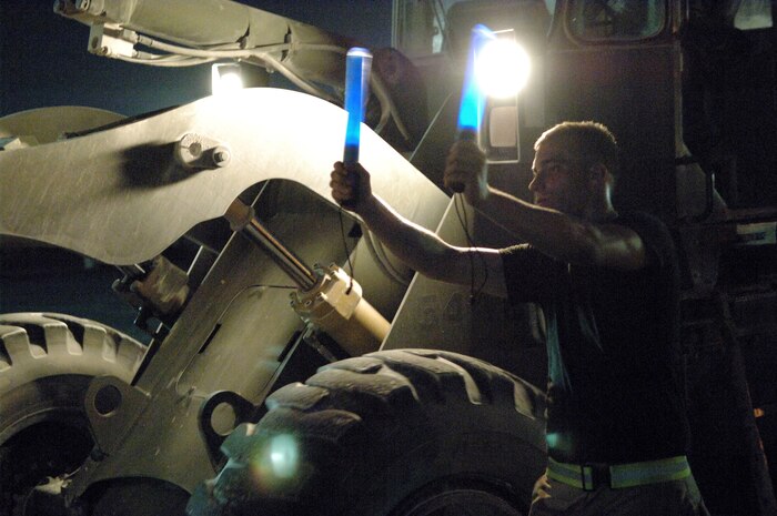 Senior Airman David Marcum, 437th Aerial Port Squadron ramp services specialist, deployed to Southwest Asia with the 8th Expeditionary Air Mobility Squadron, uses light batons to guide a 10K all-terrain forklift laden with cargo heading to a 60K-loader for transfer to an awaiting C-17. (Air Force photo/Master Sgt. Greg Kunkle)