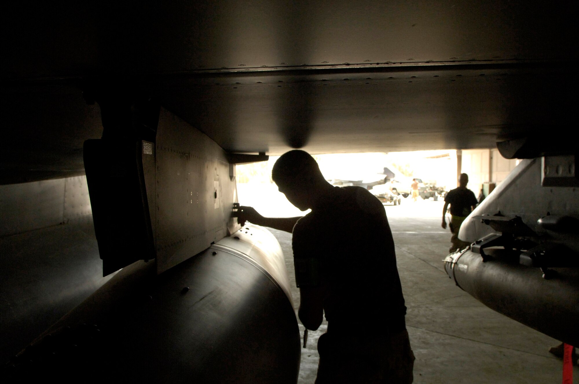 Senior Airman Mark Grabner, a weapons load crew member for the 332nd Expeditionary Aircraft Maintenance Squadron at Balad Air Base, Iraq, removes an impulse charge from the wing pylon holding the external fuel tank on an F-16 Fighting Falcon.  The impulse charge, when activated, is used to jettison the external fuel tank. (U.S. Air Force photo/Senior Airman Travis Edwards)