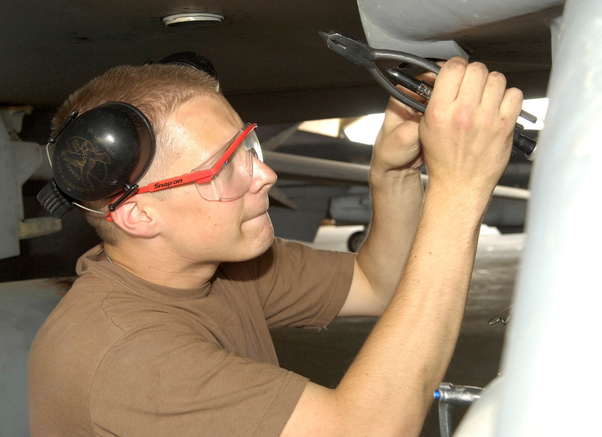 Tech. Sgt. James Trixler, a weapons mechanic for the 332nd Expeditionary Aircraft Maintenance Squadron at Balad Air Base, Iraq, tightens a safety wire on the wing pylon of an F-16 Fighting Falcon.  This maintenance helps ensure the bolts holding the pylon to the wing don't loosen during flight. (U.S. Air Force photo/Senior Airman Travis Edwards)