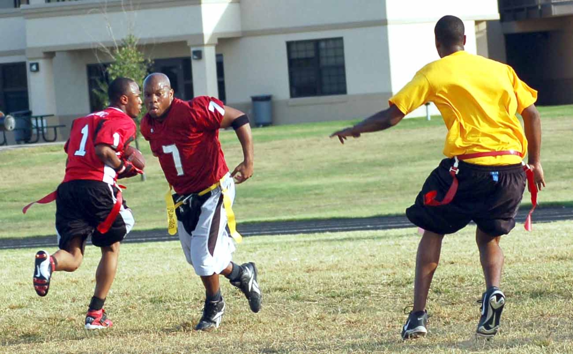 Devon Taylor (7), quarterback for the 552nd Operational Support Squadron, hands off to Jeremy Smith (1) on a reverse while 965th Airborne Air Control Squadron defender Gerard West prepares to stop the play. The 552nd OSS won the Oct. 3 game 6-0. (Air Force photo by John E. Banks)
