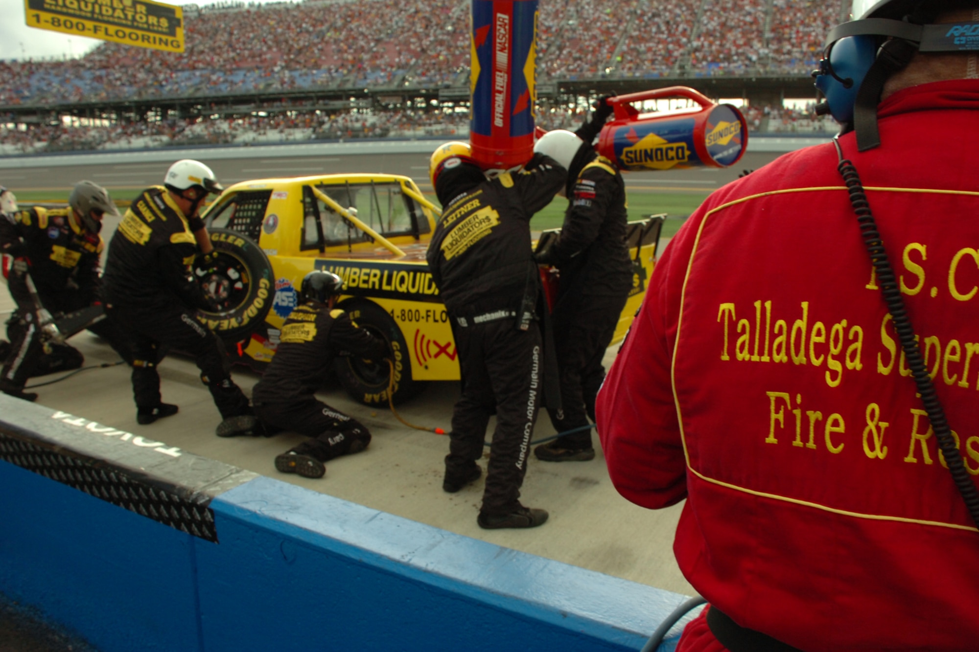 TALLADEGA, Ala. -- Tech. Sgt. Jimmy Reed, Eglin Air Force Base, Fla., firefighter and Air Force reservist at Keesler AFB, Miss., stands watch over the action in the pits as the No. 30 team performs a quick pit stop Oct. 6 during the NASCAR Craftsman Truck Series race. John Piccuito, J.R. Suddarth and Sergeant Reed, Eglin Air Force Base firefighters, are among a group of firefighters from all over the country that go to the spring and fall Talladega NASCAR races to make sure the drivers and race teams are safe. They provided safety for the Friday night Automobile Racing Club of America RE/MAX Series race, the NASCAR Craftsman Truck Series race on Saturday and the NASCAR Nextel Cup Series race on Sunday. The No. 30 team went on to win the race. (U.S. Air Force photo by Staff Sgt. Mike Meares)