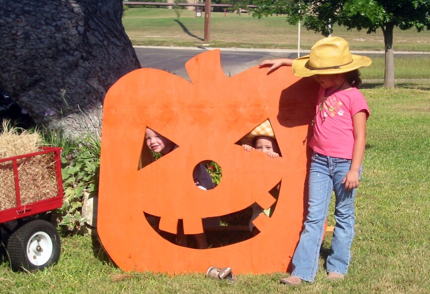 LAUGHLIN AIR FORCE BASE, Texas -- Alex Hall, daughter of Capt. Douglas Hall, 47th operations Support Squadron, and Carla Hall, Joseph Butters Jr., son of 1st Lt. Joseph Butters, 85th Flying Training Squadron, and Lady Butters, and Allie Clark, daughter of Col. Dan Laro Clark, 47th Flying Training Wing Vice Commander, and Susan Clark, play with a wooden jack-o-lantern to get in the spirit for the Fall Festival Oct. 11 at the Laughlin AFB Fam Camp.    
