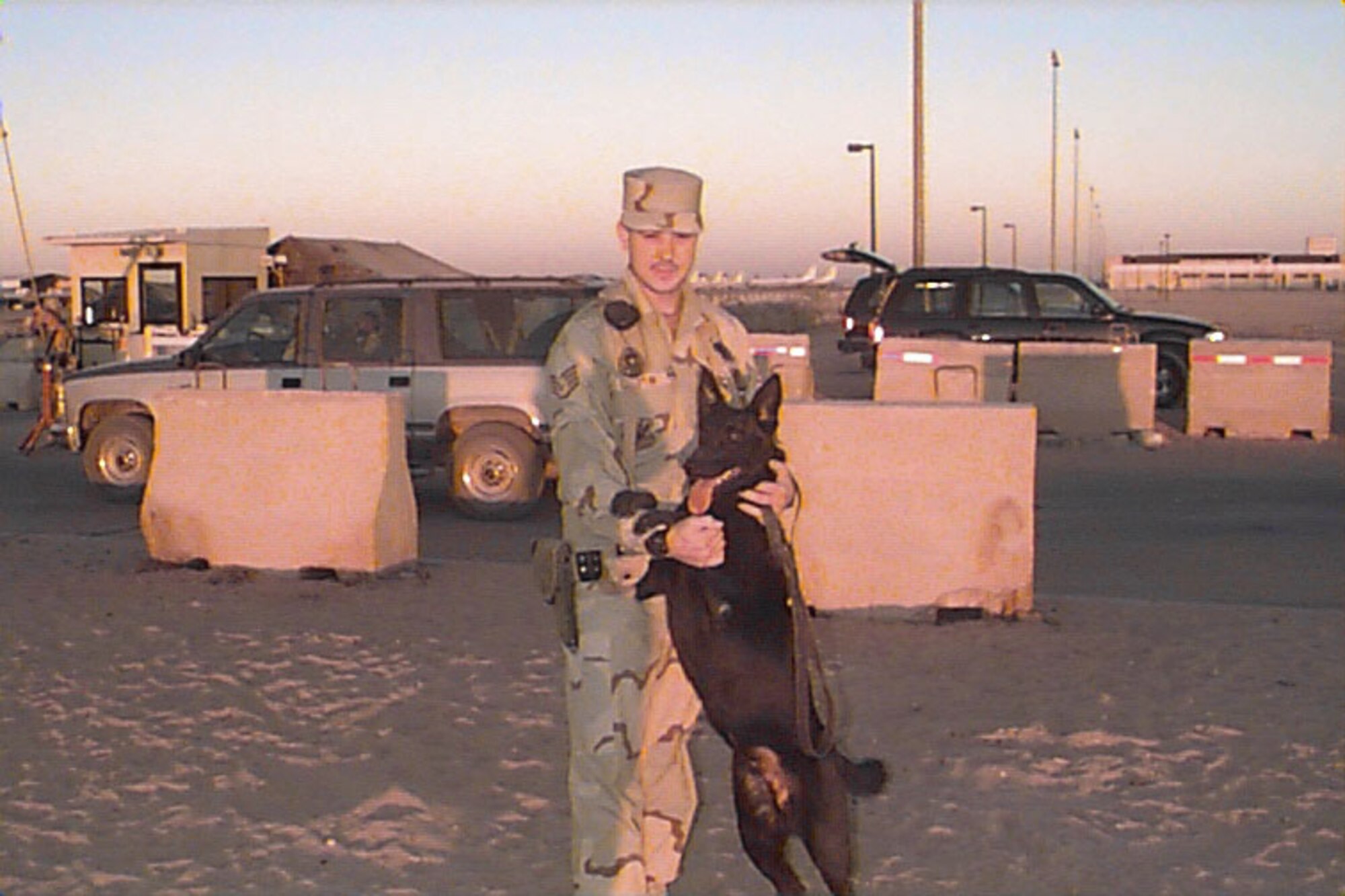 Tech. Sgt. Jon Camplin, 95th Security Forces Squadron flight chief, and his military companion Cheeta pose for the camera during their first deployment to Saudi Arabia in September 1998. Sergeant Camplin was Cheeta's first handler, and Cheeta was Sergeant Camplin's first military working dog. (Courtesy photo)