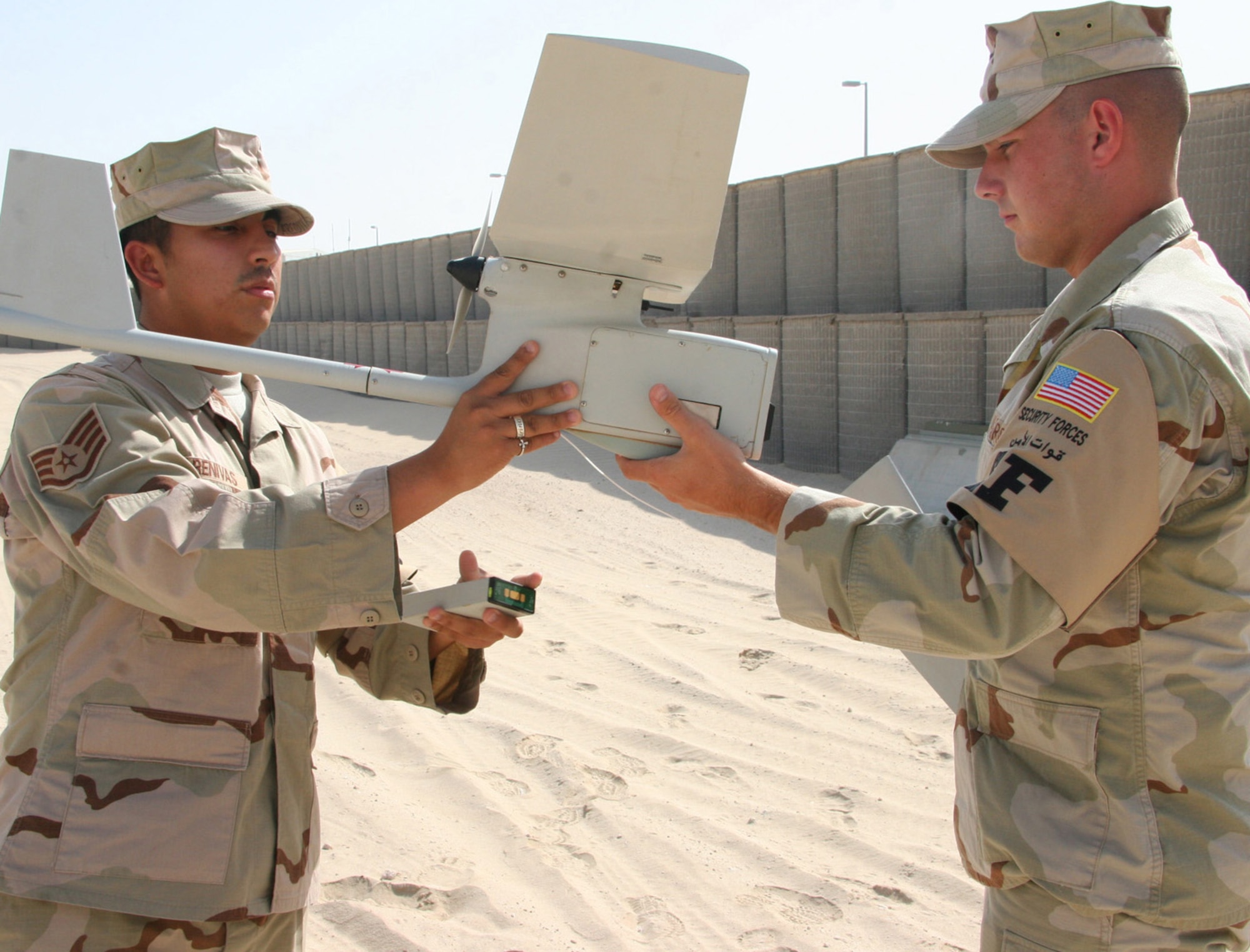 After its mission, the Raven B small unmanned aerial vehicle lands and breaks into pieces.  Staff Sgt. Karlo Arenivas (left) and Airman 1st Class James Gould, 380th Expeditionary Security Force Squadron Force Protection Airborne Surveillance System specialists, demonstrate how the Raven is recovered and then readied for a new mission. (U.S. Air Force Photo/Master Sgt. Ruby Zarzyczny)