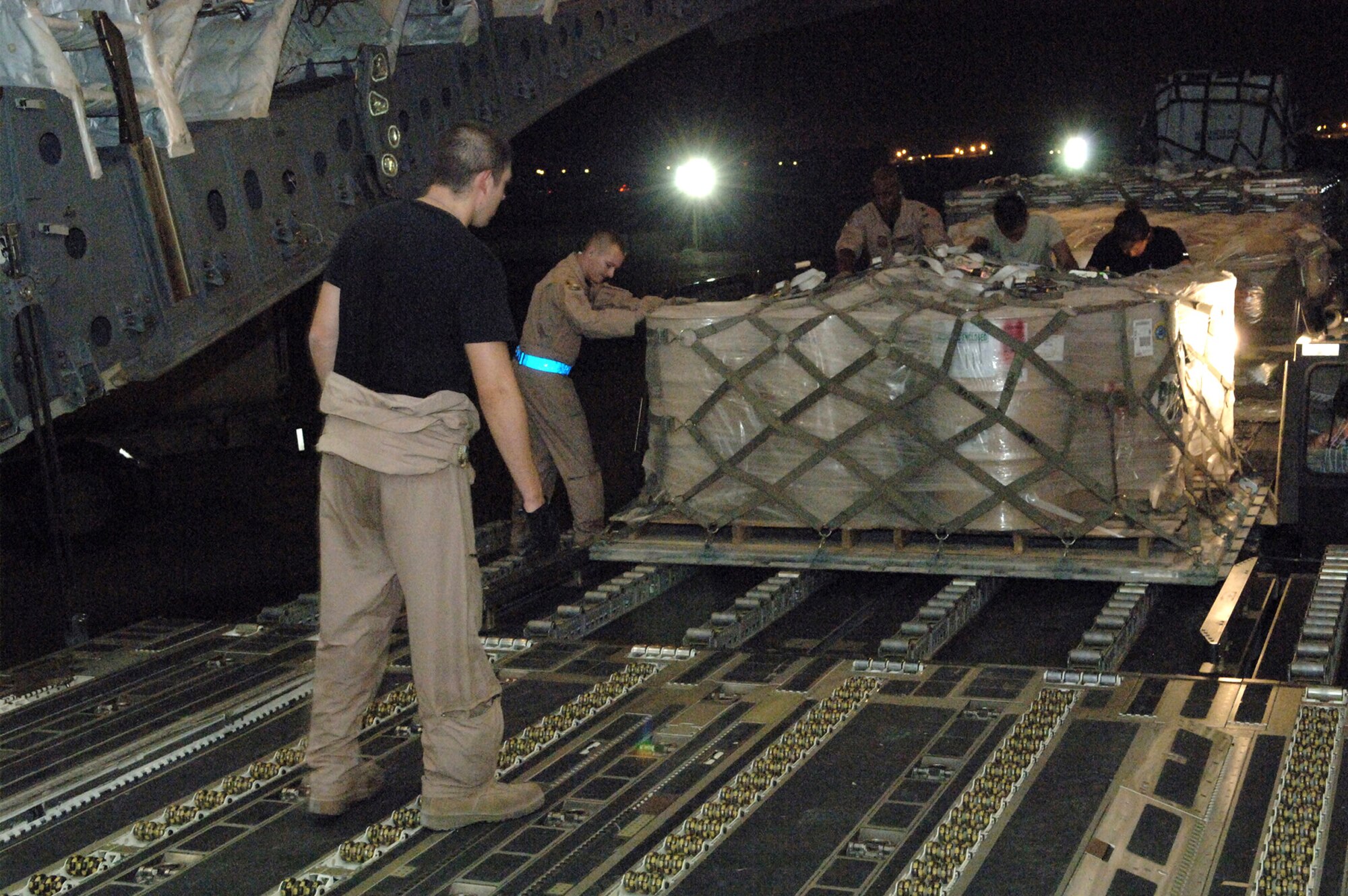 Senior Airman Stephen Knapp, 816th Expeditionary Airlift Squadron loadmaster, observes as team members from the 8th Expeditionary Air Mobility Squadron push a pallet of supplies onto a C-17 Globemaster III from a 60K loader here. Airman Knapp is deployed from McGuire Air Force Base, N.J. (U.S. Air Force photo/Master Sgt. Greg Kunkle)