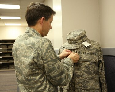 Brig. Gen. Darrell Jones, a former 37th Training Wing commander at Lackland AFB, Texas, fits an Airman Battle Uniform on a mannequin at Air Force Clothing Initial Issue Oct. 3, 2007. The new ABU comes in 236 different sizes for both male and female Airmen. (USAF photo by Robbin Cresswell)