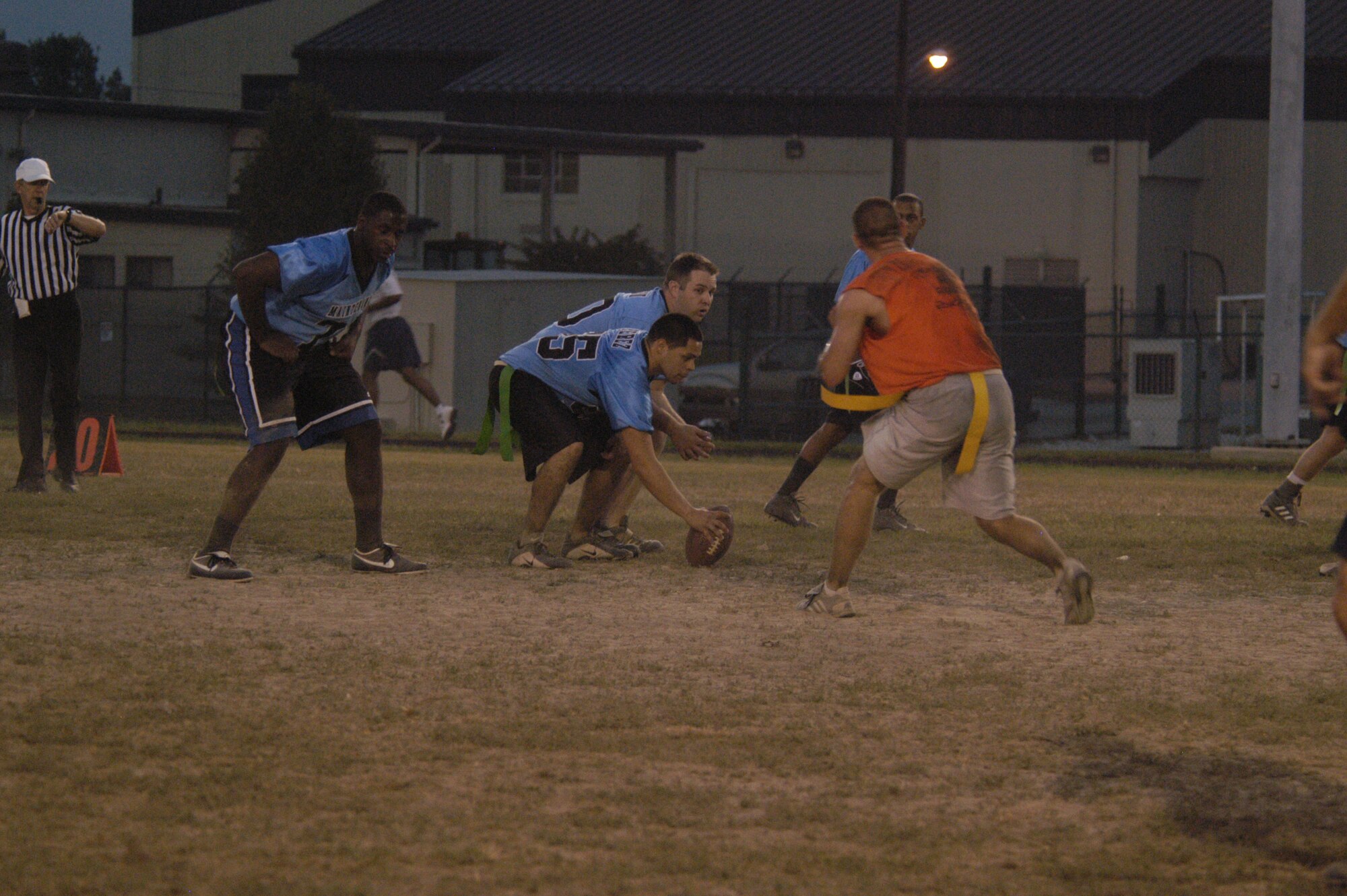 Members of the CPTS/OG  (orange) and MXS (blue) line up before the ball is hiked during Tuesday night’s intramural flag football game. CPTS/OG defeated the Maintainers 6 - 0. (U.S. Air Force photo/Airman Shen-Chia Chu)                                