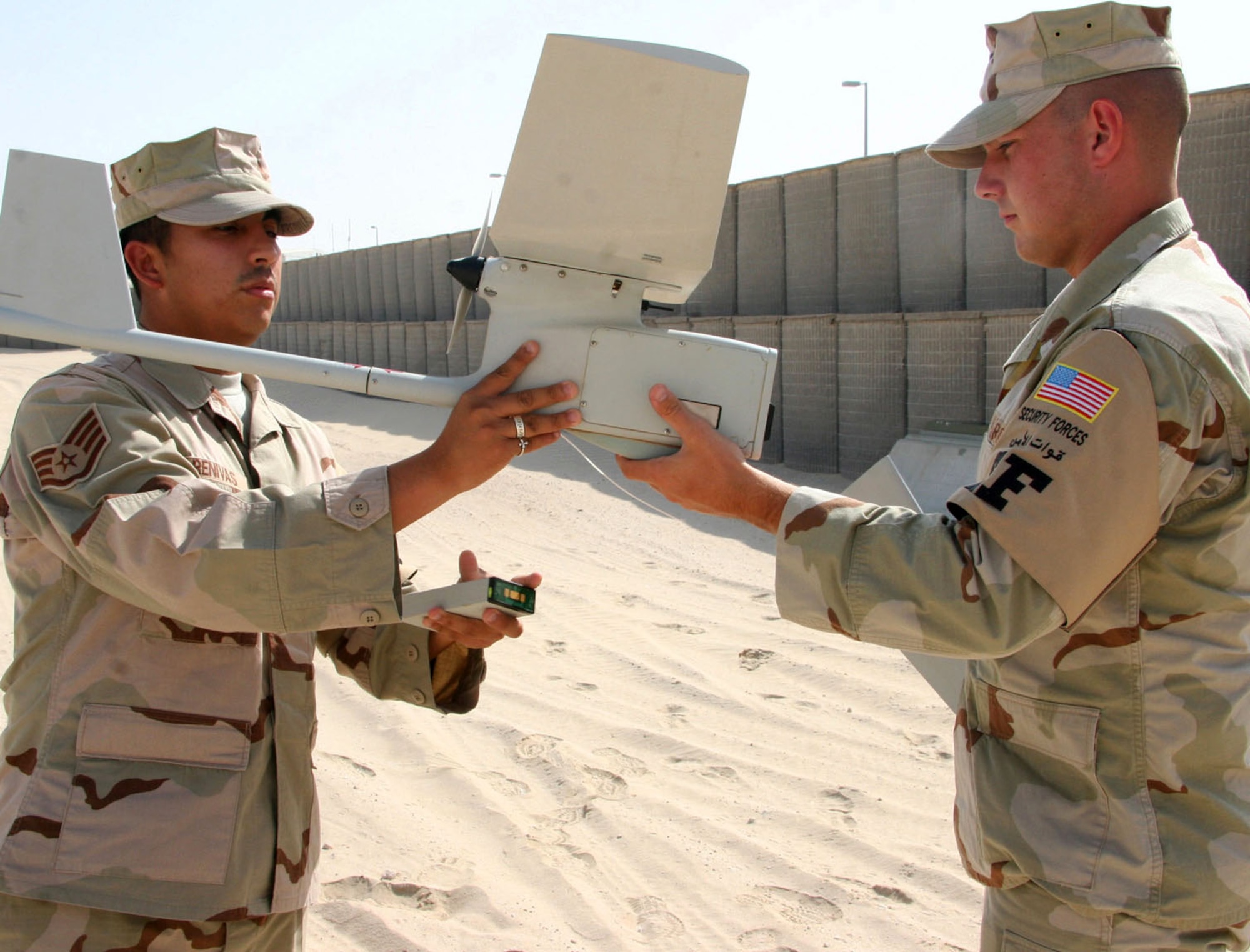 Staff Sgt. Karlo Arenivas (left) and Airman 1st Class James Gould demonstrate how the Raven B, a small unmanned aerial vehicle, is readied for a new mission Oct. 6. Following a mission, when the Raven lands it often breaks into pieces. It is then recovered, repaired and readied for a new mission. The Airmen are force protection airborne surveillance system specialists with the 380th Expeditionary Security Force Squadron. (U.S. Air Force photo/Master Sgt. Ruby Zarzyczny) 