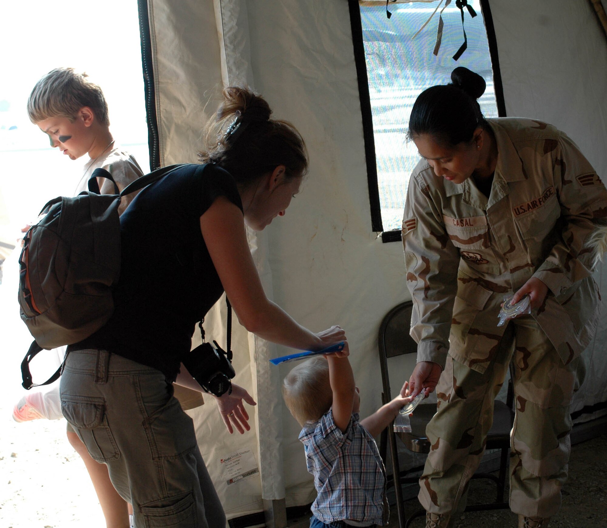 Senior Airman Carmi Casal, 60th Comptroller Squadron, hands a deployer his squadron patch during the Kids Understanding Deployment Operations event Oct. 3. Deployers received a KUDOS bag, complete with KUDOS bars, military challenge coins, coloring books, gift items from the chapel, AAFES and Red Cross. (U.S. Air Force photo/Staff Sgt. Candy Knight)