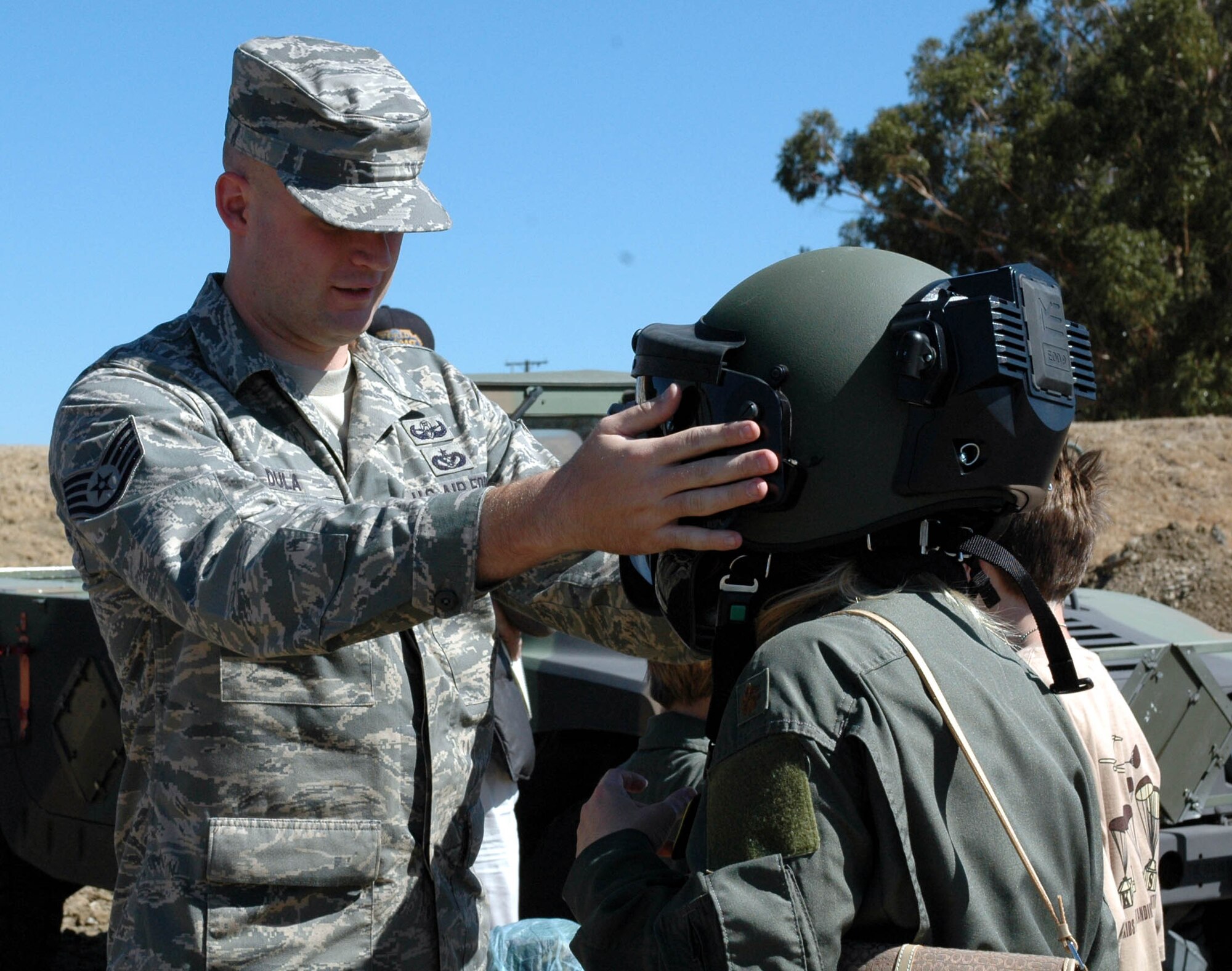 Staff Sgt. Richard Dula, 60th Civil Engineer Squadron's Explosive Ordinance Disposal flight, helps a deployer suit up during the Kids Understanding Deployment Operations event Oct. 3. During the event, children, ages 18 and younger, also viewed demonstrations from the 60th CES fire department and the 60th Medical Operations Support Squadron. (U.S. Air Force photo/Staff Sgt. Candy Knight)