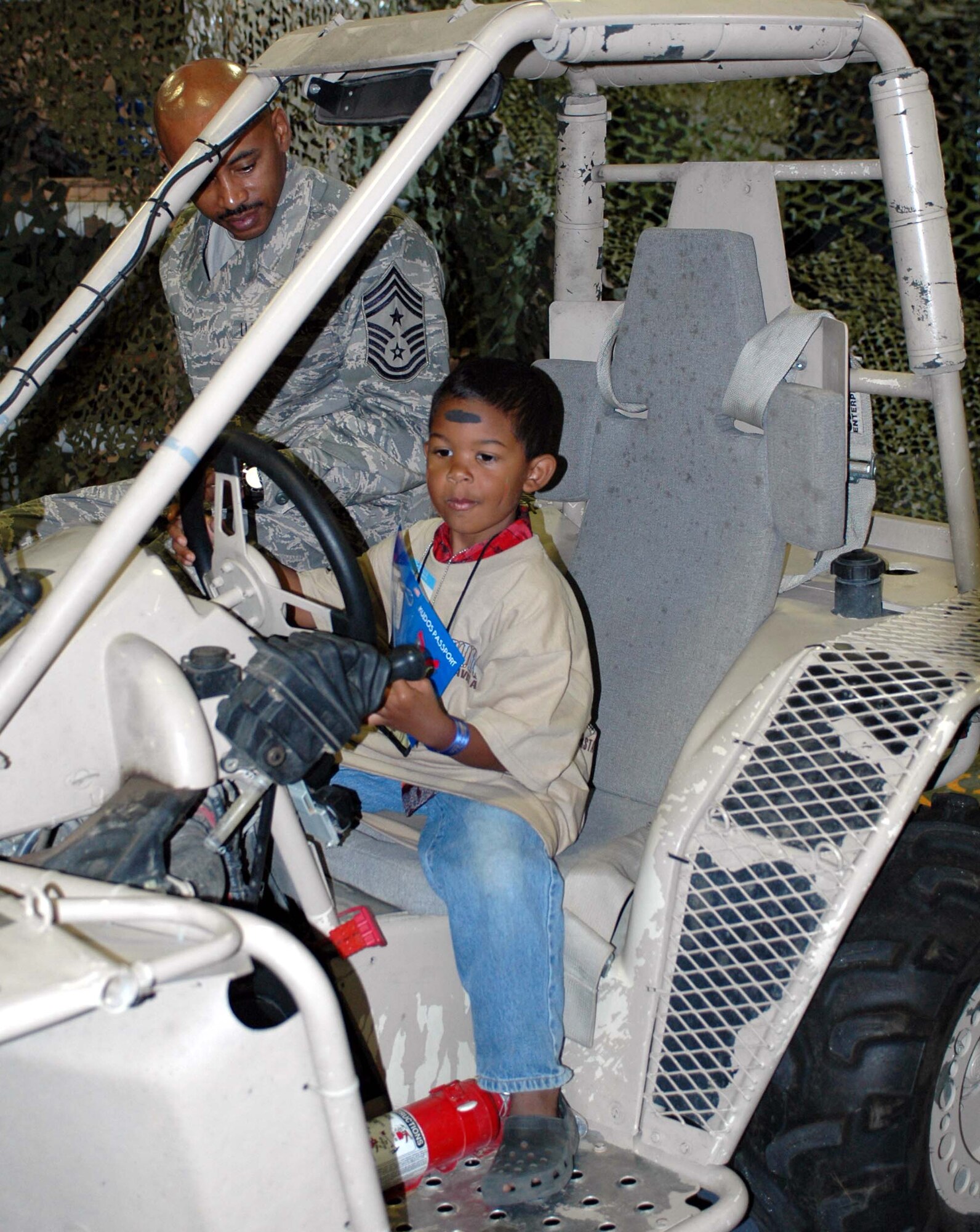 Chief Master Sgt. Michael Williams, 60th Air Mobility Wing command chief, helps a KUDOS deployer get his dune buggy into gear during the Kids Understanding Deployment Operations event Oct. 3. Military family members also viewed demonstrations from the 60th Civil Engineer Squadron's Explosive Ordinance Disposal robot, fire department and the 60th Services Squadron’s Mobile Kitchen Unit. (U.S. Air Force photo/Staff Sgt. Candy Knight)