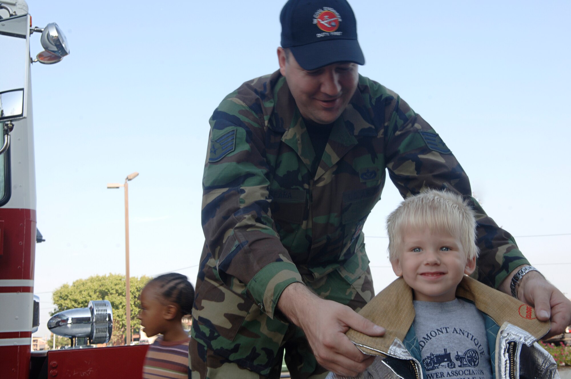 Staff Sgt. Kevin Ferrara, 1st Civil Engineer Squadron firefighter, places his fire coat over Cole Zadjel during a fire prevention week briefing at the Russ Child Development Center here Oct. 9. The goal of Fire Prevention Week is to educate children and adults on fire safety. Cole is the son of Staff Sgt. Erik Zajdel, 1st Security Forces Squadron training instructor, and Staff Sgt. Liza Zajdel, 1st Medical Operations Squadron mental health technician. (U.S. Air Force photo/Airman 1st Class Vernon Young)
