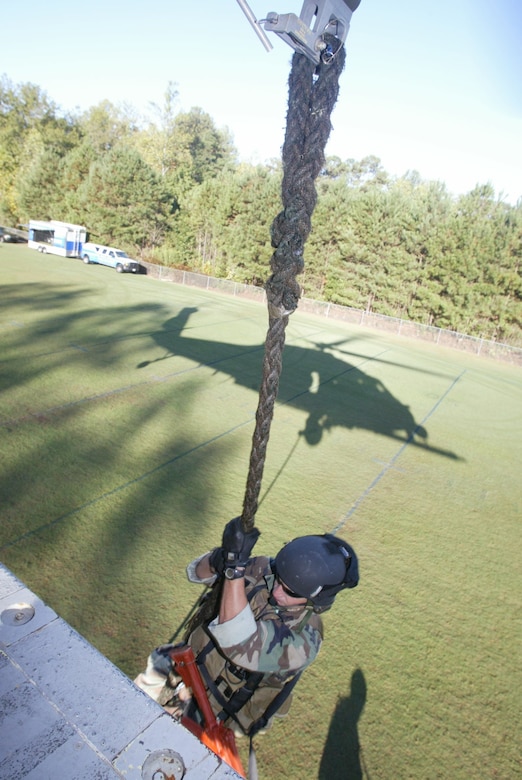 A pararescueman from the 301st Rescue Squadron at Patrick AFB, Fla., lowers himself out the side of an HH-60 Pavehawk during a tactical rescue display at Etowah High School in Woodstock, Ga. Oct. 10. The drop-in was part of Air Force Week Atlanta. Students were also treated to static displays from units at Dobbins Air Reserve Base, Ga., as well as a performance from the Air Force Honor Guard Drill Team. (U.S. Air Force photo/Don Peek) 