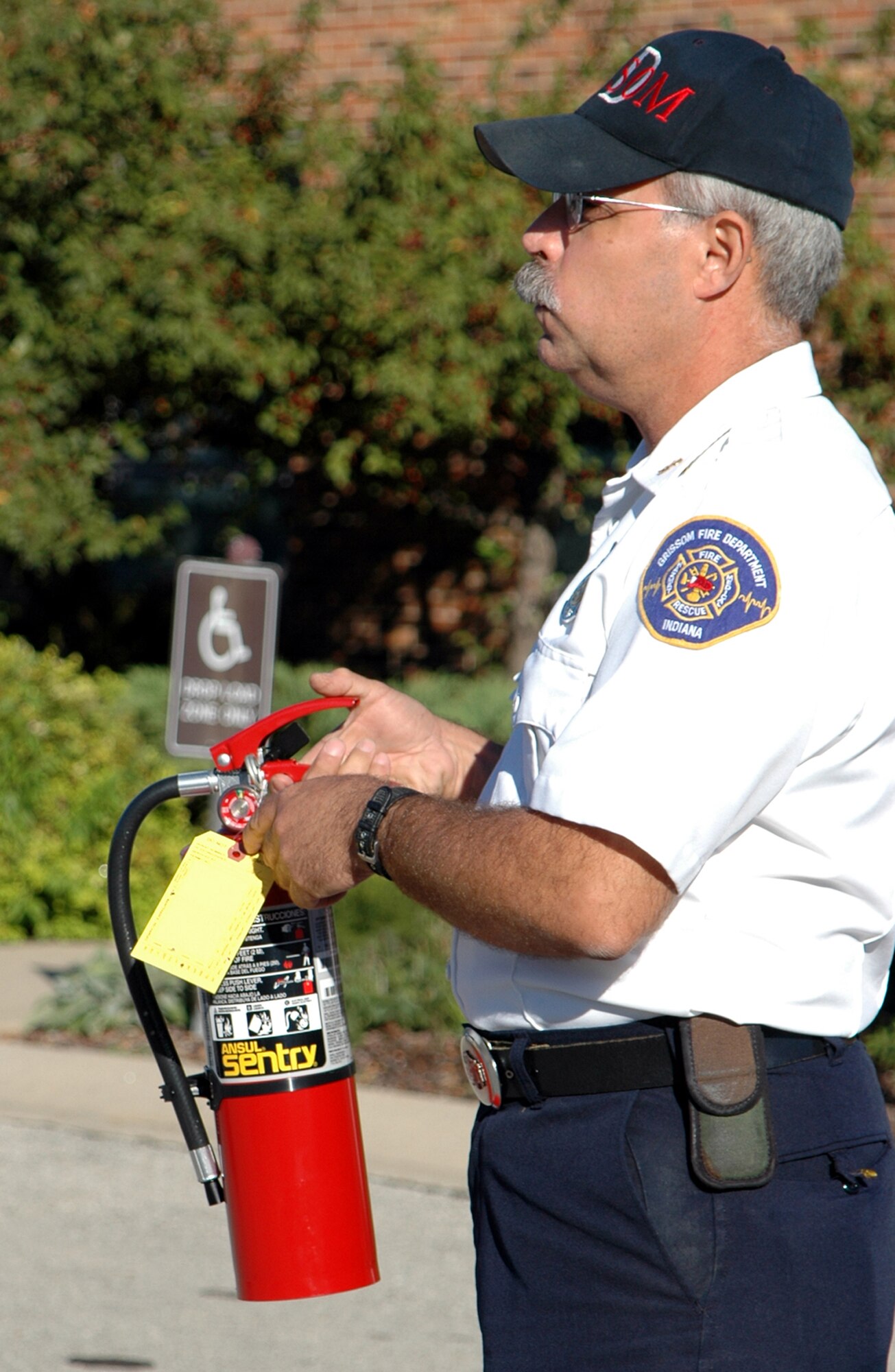 GRISSOM AIR RESERVE BASE, Ind., -- Les McConnell, assistant chief of fire-prevention at the Grissom Fire Department, explains how to inspect a fire extinguisher during a fire prevention week activity at Grissom. When inspecting a fire extinguisher there should not be any yellow or white powder inside of the hose. This means that the extinguisher has been discharged and may not be working. (U.S. Air Force photo/ SrA Carl Berry)