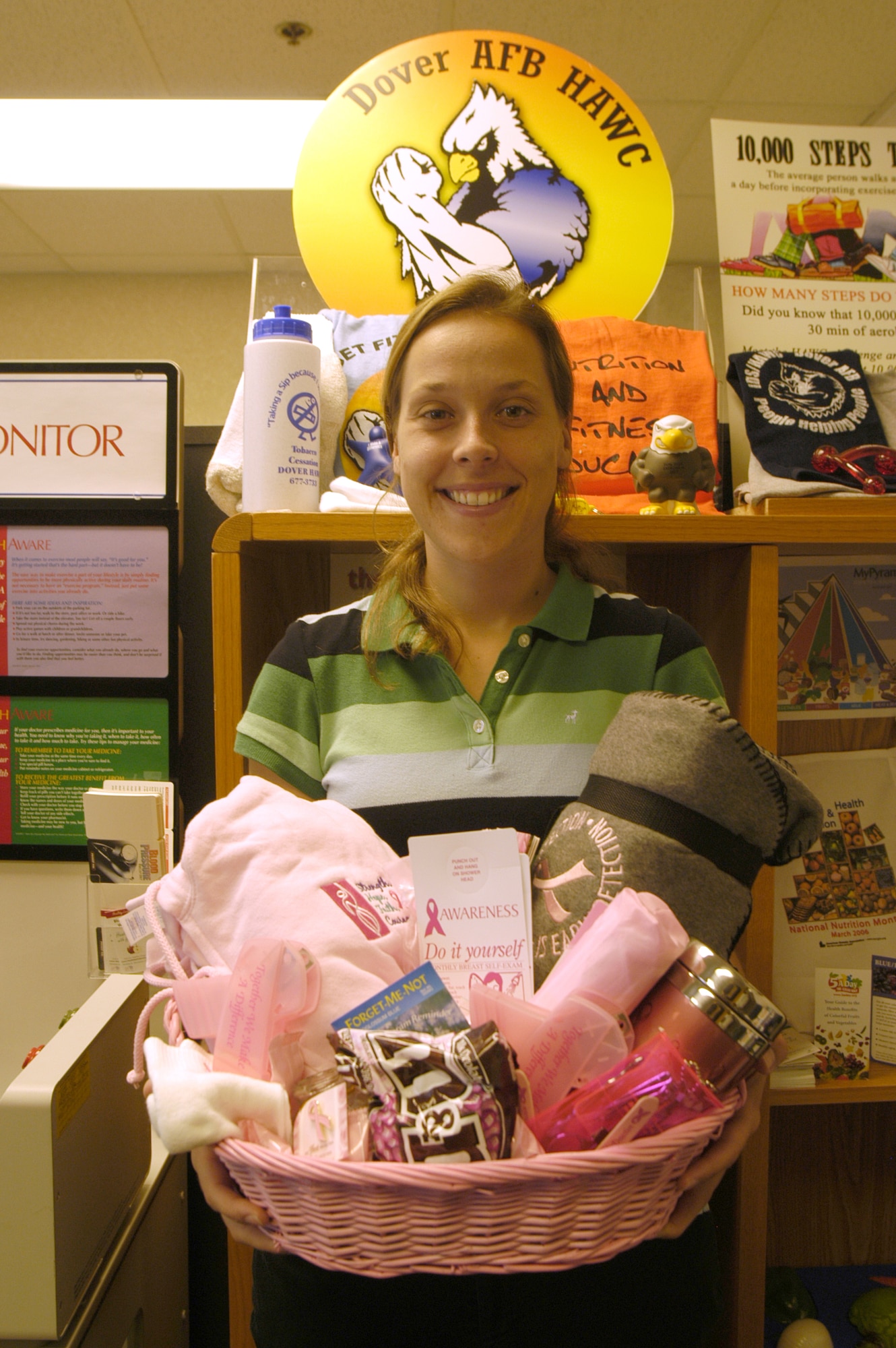 Nicole Voyer, the Health and Wellness Center’s new health education program manager, showcases the Breast Cancer Awareness basket worth over $75. A few of the items include: a pink sweatshirt, coffee mug, umbrella, fleece blanket and more. Participants can win the basket during the months of October, November and December by having a mammogram exam. Contact the medical group for referral information. (U.S. Air Force photo/Airman Shen-Chia Chu)                             