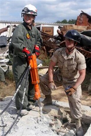 Cpl. Michael Meyer (right), a rescue technician with the Technical Rescue Platoon, Headquarters and Service Company, Chemical Biological Incident Response Force, II Marine Expeditionary Force, instructs a Marine spouse on how to drill concrete during Jane Wayne Day here Oct. 11. In a real-world incident, Marines may need to drill through concrete walls or floors to rescue casualties.