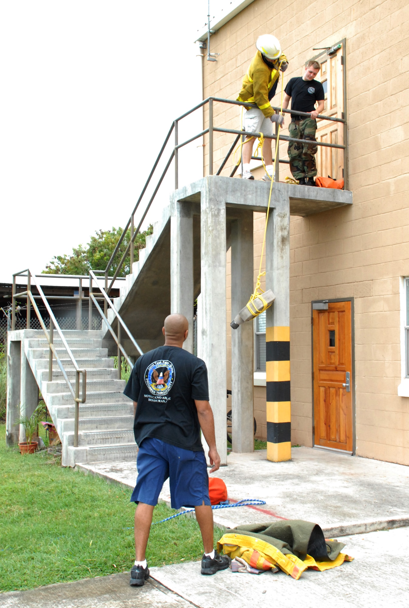 SOTO CANO AIR BASE, Honduras -- Staff Sgt. Aaron Mickle waits his turn in Soto Cano's Fire Muster relay as his teammate Tech. Sgt. Rob Russell, both Armed Forces Network, pulls a hose up to the second floor.  The relay challenge was Soto Cano Fire Department's closing event for Fire Prevention Week.  (U.S. Air Force photo by 1st Lt. Erika Yepsen)