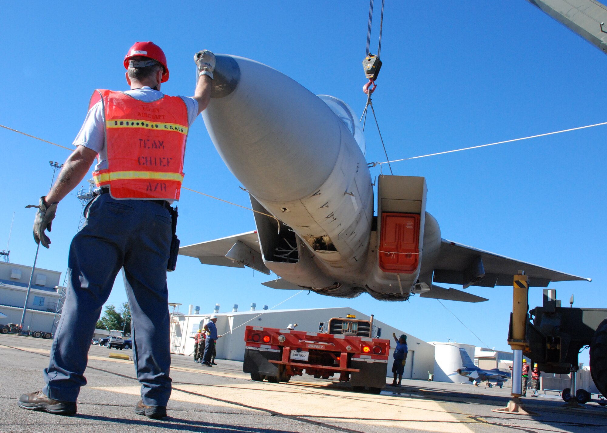 EGLIN AIR FORCE, Fla. --  Dennis Schlitter, DynCorp Aero-repair, helps position the hovering F-15 as a driver backs the flatbed trailer underneath it for transport to an Eglin range Oct. 12. Indyne Inc. U.S. Targets and the 46th Test Wing is moving a F-15 to Range 52 for future testing missions. The crew, lifted the aircraft, collapsed the landing gear and hoisted it onto a flatbed trailer to be transported to Range 52 off Range Road 213. They are scheduled to move the jet beginning at 2 a.m. Oct. 13. (U.S Air Force Photo by Staff Sgt. Mike Meares)