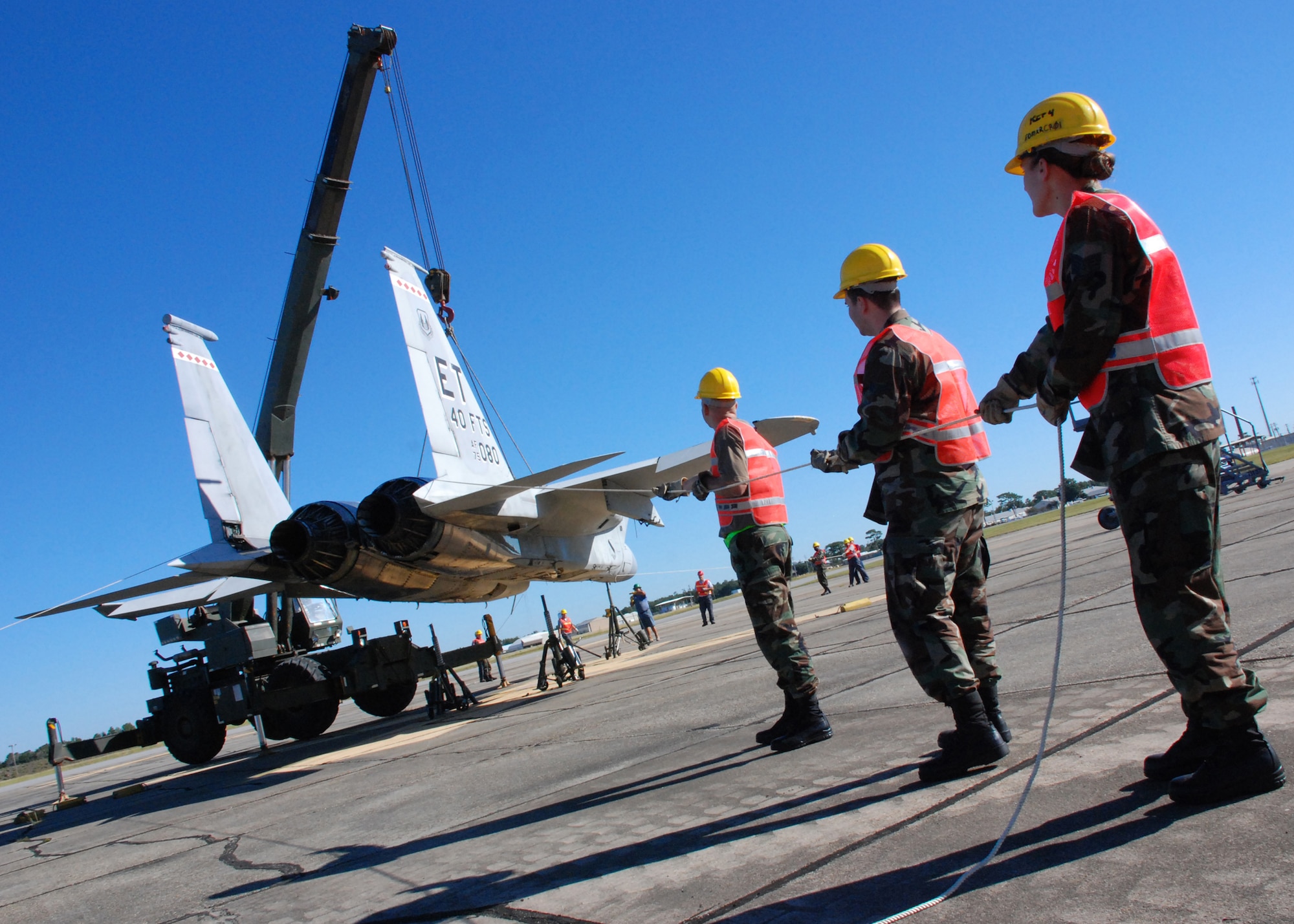 EGLIN AIR FORCE, Fla. -- Staff Sgt. Jeremy Buntz, Airman 1st Class Warren Rendon and Staff Sgt. Destiny Harp, 33rd Maintenance Sqaudron, helps hold an F-15 steady as it hangs from a crane an is loaded onto a flatbed trainler for transport Oct. 12. Indyne Inc. U.S. Targets and the 46th Test Wing is moving the F-15 to Range 52 for future testing missions.The crew, lifted the aircraft, collapsed the landing gear and hoisted it onto a flatbed trailer to be transported to Range 52 off Range Road 213. They are scheduled to move the jet beginning at 2 a.m. Oct. 13. (U.S Air Force Photo by Staff Sgt. Mike Meares)