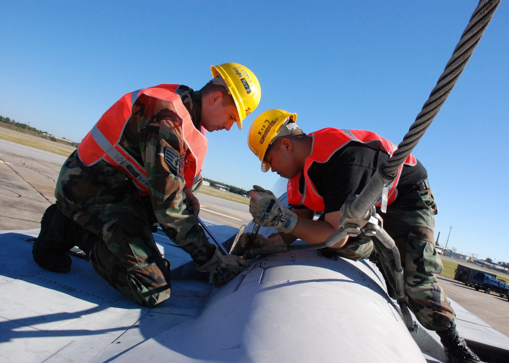 EGLIN AIR FORCE, Fla. -- Staff Sgt. Paul Hickey and Senior Airman Kristopher Tuason, 33rd Maintenance Sqaudron, tighter the bolt on a cable to hoist an F-15 into the air by a crane and loaded onto a flatbed trainler for transport Oct. 12. Indyne Inc. U.S. Targets and the 46th Test Wing is moving the F-15 to Range 52 for future testing missions.The crew, lifted the aircraft, collapsed the landing gear and hoisted it onto a flatbed trailer to be transported to Range 52 off Range Road 213. They are scheduled to move the jet beginning at 2 a.m. Oct. 13. (U.S Air Force Photo by Staff Sgt. Mike Meares)