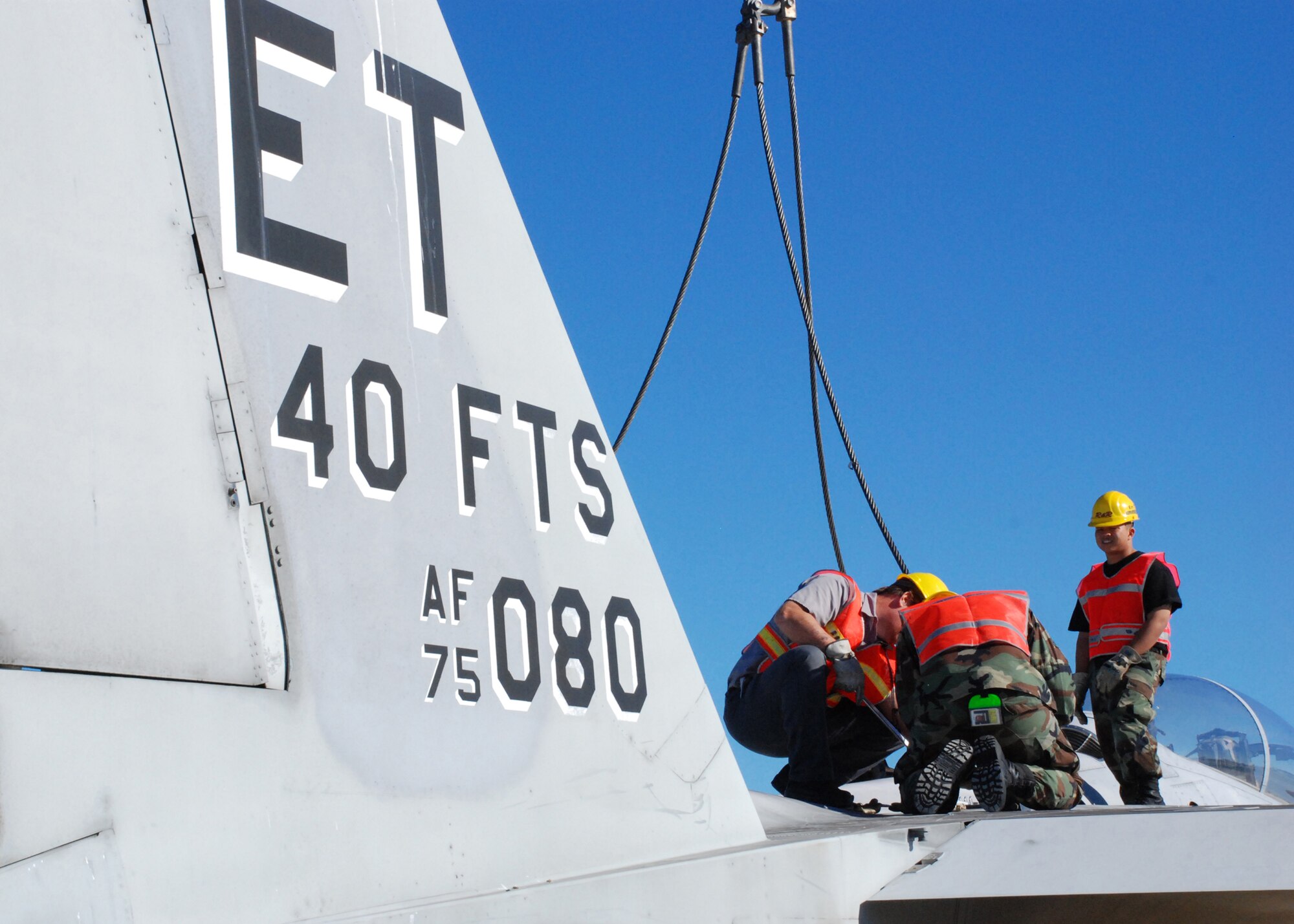 EGLIN AIR FORCE, Fla. -- Members of the 33rd Maintenance Sqaudron help secure the cables to an F-15 to be hoisted by a crane and loaded onto a flatbed trainler for transport Oct. 12. Indyne Inc. U.S. Targets and the 46th Test Wing is moving the F-15 to Range 52 for future testing missions.The crew, lifted the aircraft, collapsed the landing gear and hoisted it onto a flatbed trailer to be transported to Range 52 off Range Road 213. They are scheduled to move the jet beginning at 2 a.m. Oct. 13. (U.S Air Force Photo by Staff Sgt. Mike Meares)