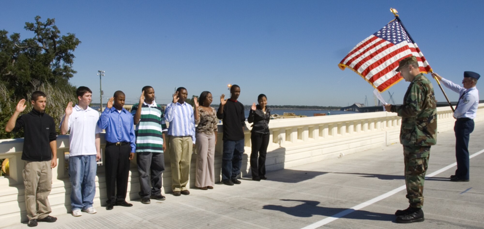 BILOXI, Miss.--Recruits recite the oath of enlistment on the soon to be opened Biloxi/Ocean Springs bridge as Maj. Chad Gibson, 403rd Wing administers the oath. These recruits participated in the 403rd Wing Recruiting Squadron's annual Mass Enlistment Ceremony. The bridge, which connects the communities of Biloxi and Ocean Springs, Miss. is slated to open two lanes Nov. 1. It was destroyed by Hurricane Katrina Aug. 29, 2005. The new bridge features a high rise in the middle to accomodate shipping traffic, eliminating the drawbridge which was in place before the storm. Mississippi Department of Transportation officials say the initial opening of the bridge will ease some of the traffic flow into and out of Biloxi which is located on a peninsula. Many Ocean Springs residents work in Biloxi and have been commuting many extra miles each day.