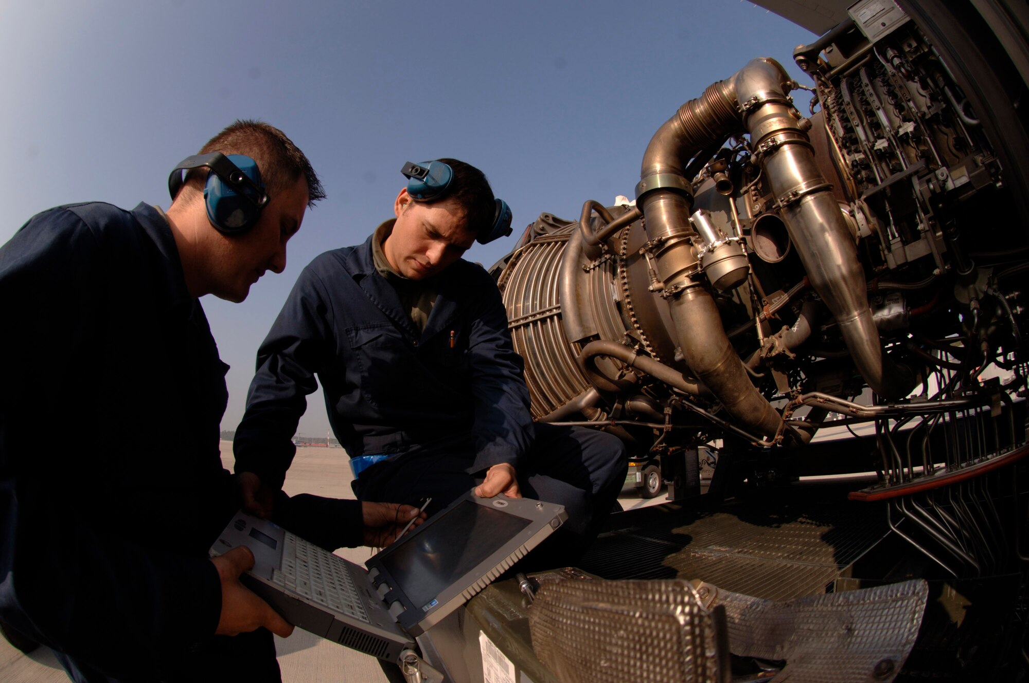 Staff Sgt. Erik Marsaln (right) and Senior Airman Bill Metz consult engine technical orders on a laptop that will guide them through an engine change-out on a C-17 Globemaster III at Ramstein Air Base, Germany, Oct. 11. The Airmen are jet engine mechanics assigned to the 723rd Air Mobility Squadron. (U.S. Air Force photo/Master Sgt. Scott Wagers) 
