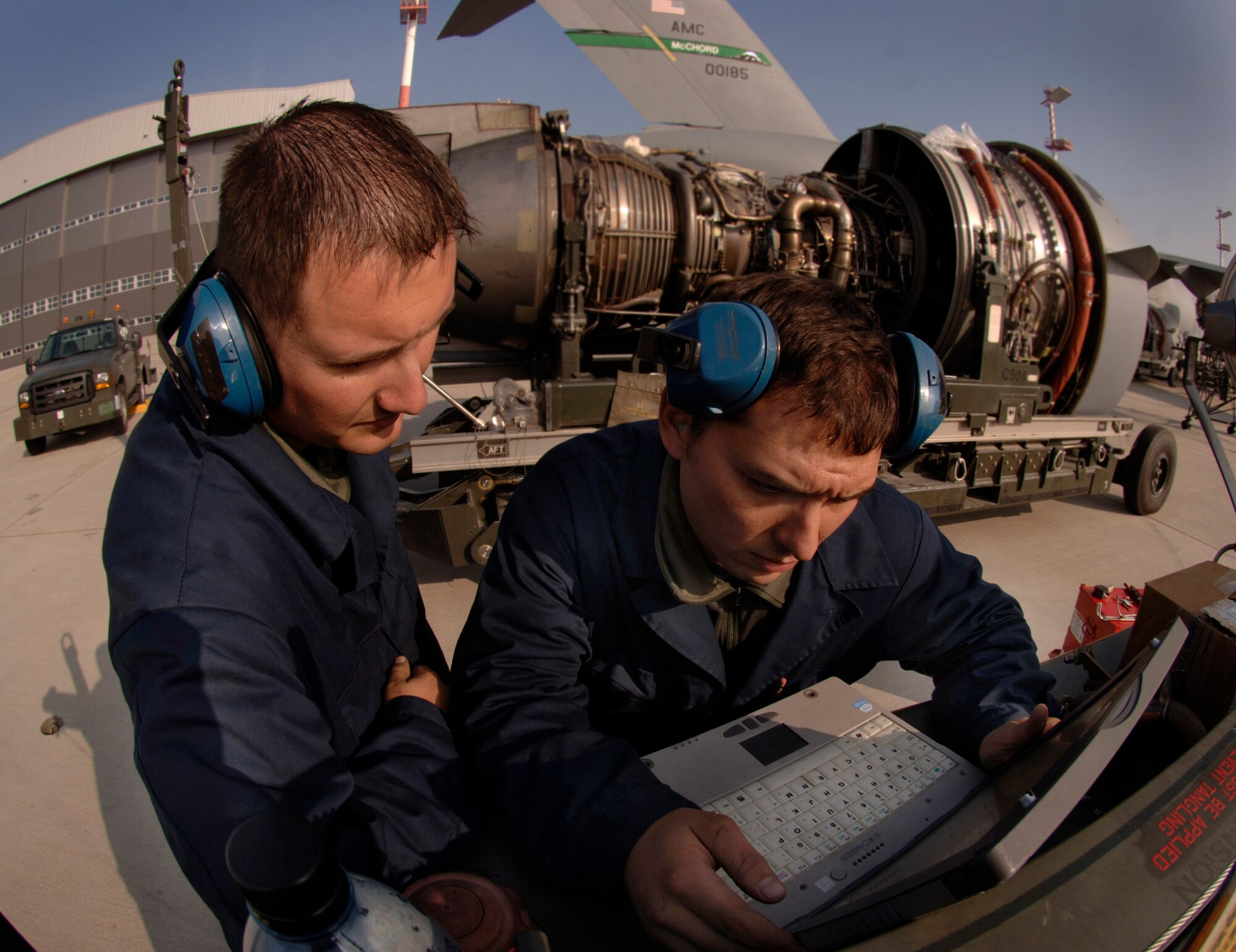 Staff Sgt. Erik Marsaln (right) and Senior Airman Bill Metz consult engine technical orders on a laptop that will guide them through an engine change-out on a C-17 Globemaster III at Ramstein Air Base, Germany, Oct. 11. The Airmen are jet engine mechanics assigned to the 723rd Air Mobility Squadron. (U.S. Air Force photo/Master Sgt. Scott Wagers) 