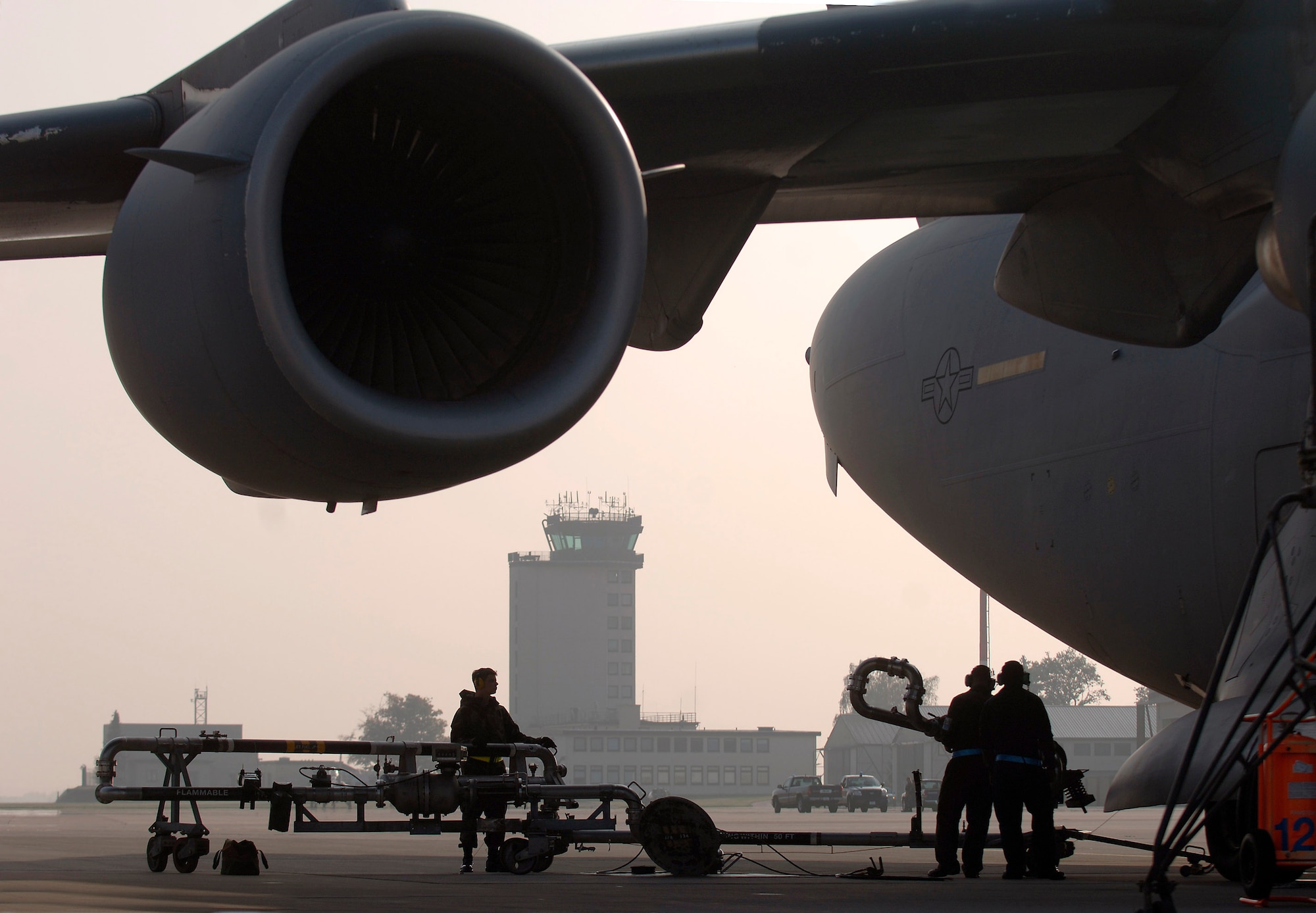 Airman 1st Class Jesse Hayes and Senior Airmen Lance Sithammalat and Rich Edward work together to pump JP-8 fuel into a C-17 Globemaster III at Ramstein Air Base, Germany, Oct. 11. Airman Hayes is a mobile fuels operator assigned to the 435th Logistics Readiness Squadron; Airmen Sithammalat and Edward are crew chiefs with the 723rd Air Mobility Squadron. (U.S. Air Force photo/Master Sgt. Scott Wagers) 
