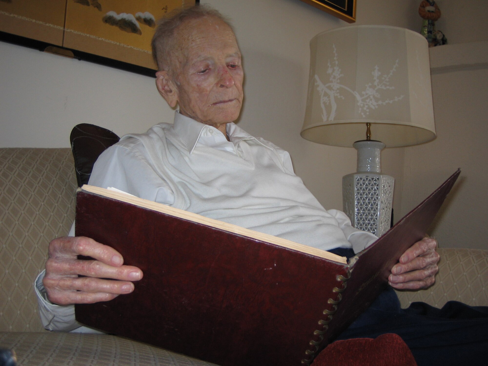 Retired Col. Walter Douglass, World War II P-51 Mustang pilot, looks through a book of Stalag Luft III, a German prison camp where he was a POW. Douglass was shot down in 1944 and taken prisoner on D-Day. The book included drawings of the prison camp and photos that were smuggled out. (photo by Tech. Sgt. Robert Zoellner)