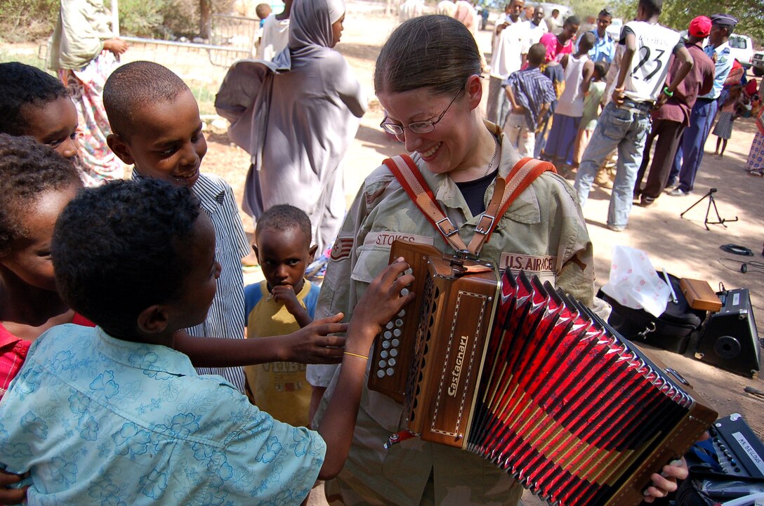 Staff Sgt. Lacey Stokes meets local children in Damerjog village, Djibouti, Oct. 9. Sergeant Stokes and other members of the U.S. Central Command Air Forces Celtic Band performed a 45-minute show and handed out gifts and toys as part of a community relations event. This is the fist time the CENTAF Celtic Band has deployed. Other members of the band are Tech. Sgts. Sherry Burt and Gail Adams, and Airmen 1st Class Brandon Richard and Amy McCann. (U.S. Air Force photo)