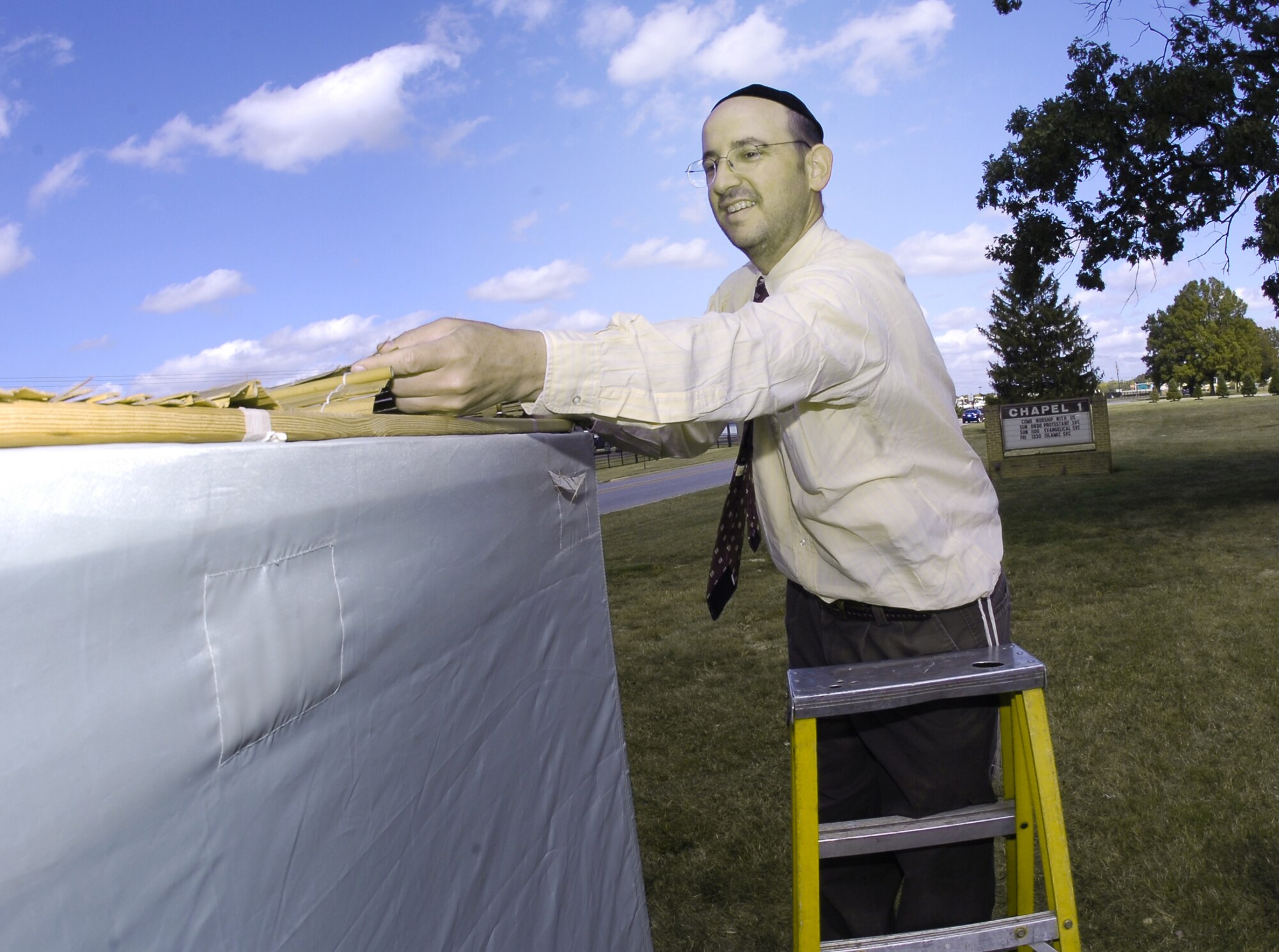 Rabbi Cohen places a reed mat roof on the Sukkoth temporary dwelling.