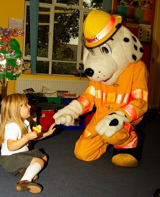 Megan McCrea, 4, greets Sparky the Fire Dog during a visit to France Class at Beck Row Primary School Oct. 9, as part of Fire Prevention Week. (U.S. Air Force photo by Karen Abeyasekere)
