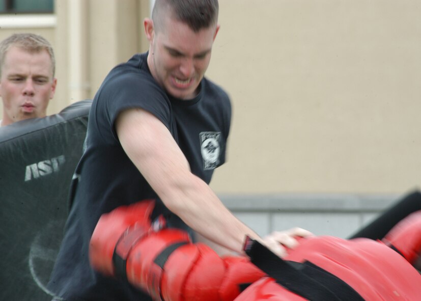 KUNSAN AIR BASE, South Korea-- 1st Lt. William Brokaw, watches as Airman 1st Class Jason Kurtzhals, pushes Staff Sgt. Vincent Reed, in the red man suit, to the ground during baton training here Oct 12. Baton certification training is done annually to instruct security forces members on intermediate use of force. Lieutenant Brokaw, Airman Kurtzhals and Sergeant Reed are assigned to the 8th Security Forces Squadron. (U.S. Air Force photo/Staff Sgt. Araceli Alarcon)
