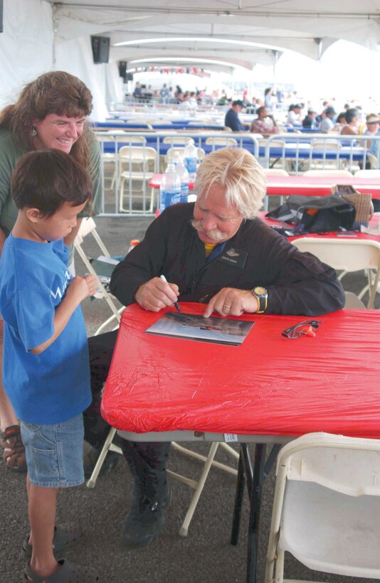 Chuck Aaron, helicopter pilot, Red Bull, autographs a photo for Nathan Chan. The eight-year-old rode the air show's Kids Kopter ride before meeting the aerobatic pilot. Chan and several families from the Make-A-Wish Foundation of Hawaii saw Aaron fly the Red Bull helicopter upside-down.