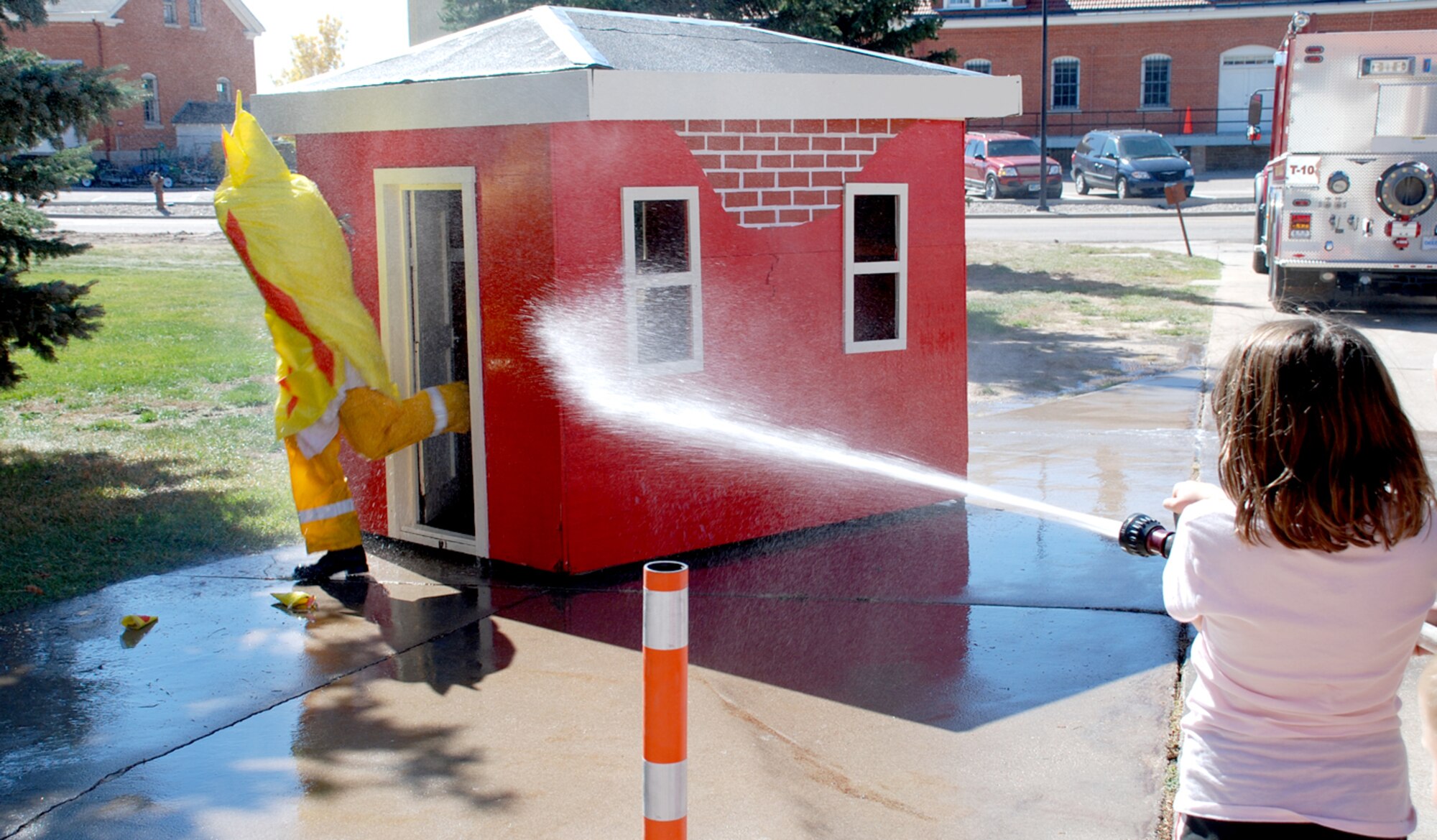 Hannah Riedel sprays a water hose at Airman 1st Class Alex Klinger, 90th Civil Engineer Squadron. Airman Klinger disguised himself as fire and the children at the open house had to ‘extinguish’ him.