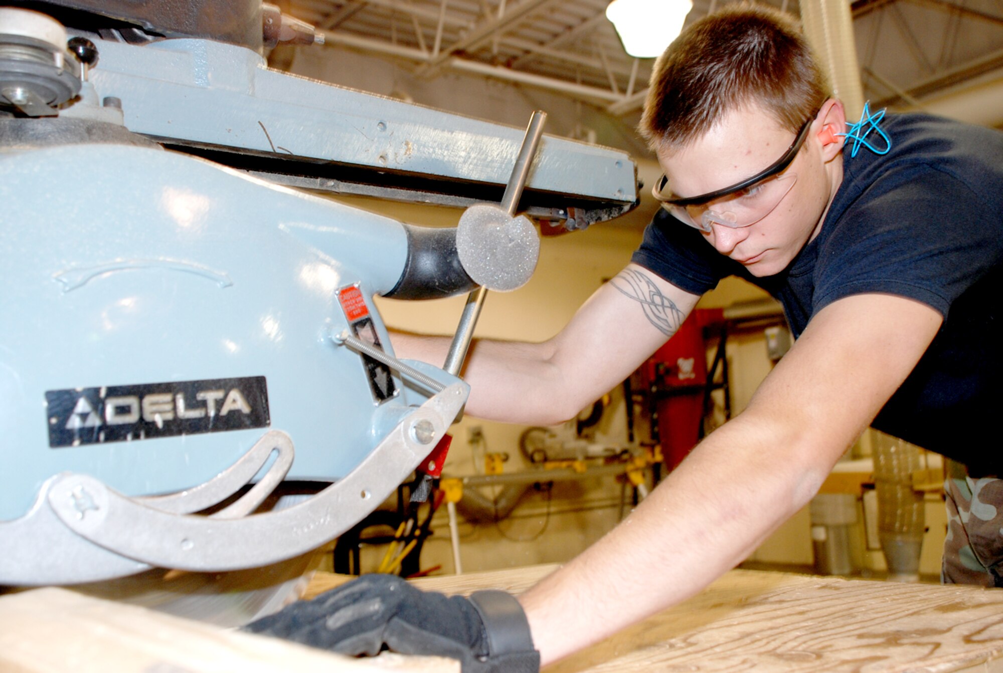 Senior Airman Bruce Sheel, cargo distribution center, cuts a piece of wood to create a specialized packing instruction. SPIs are wooden crates that have specific dimensions required by certain packages. Airman Sheel is from the 243rd Air Traffic Control Squadron at the Air National Guard (Photo by Airman 1st Class Daryl Knee).