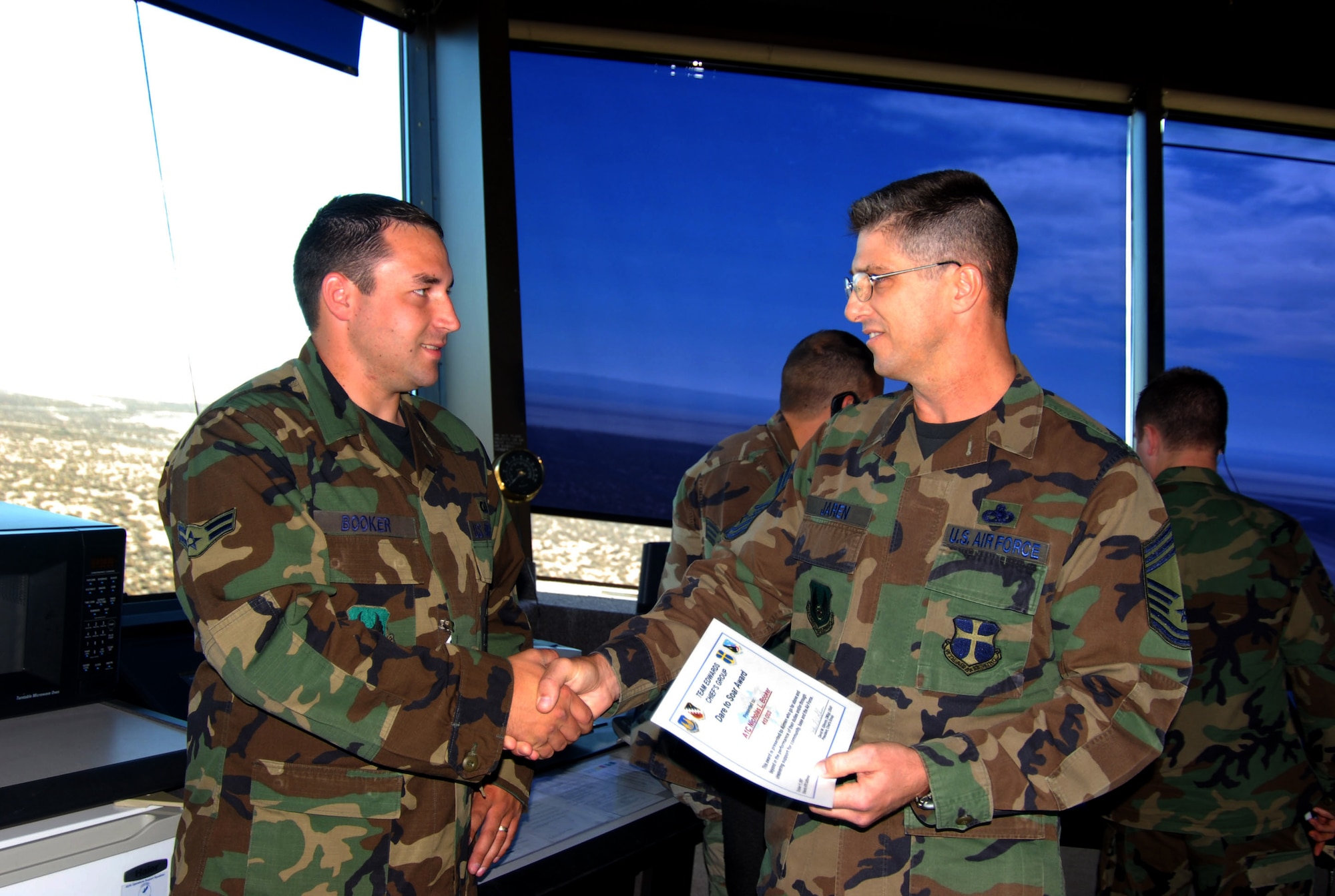 Chief Master Sgt. Eric Jaren (right), 95th Mission Support Group superintendent, congratulates Airman 1st Class Nicholas Booker (left), 412 Operations Support Squadron air traffic controller, for receiving the Chief's Group's Dare to Soar award. The Dare to Soar award is presented to Airmen for outstanding performance. (Photo by Airman 1st Class Mike Young) 