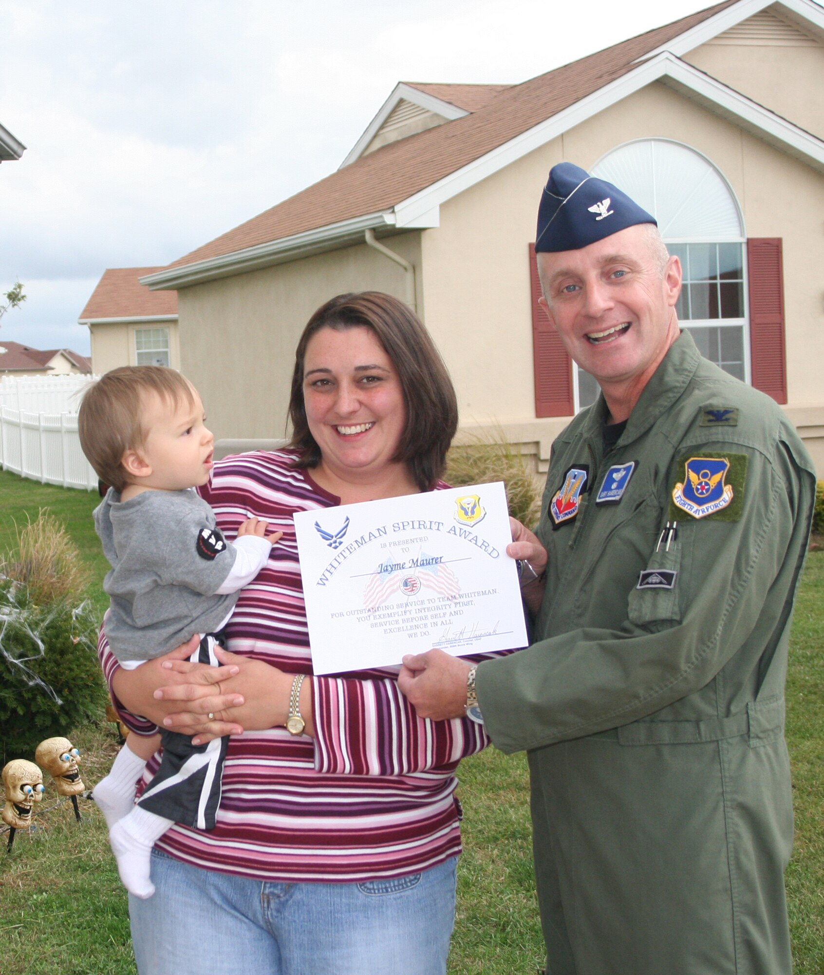 Jayme Maurer (center) receives the Whiteman Spirit Award from Col. Garrett Harencak, 509th Bomb Wing commander, Oct. 15. (U.S. Air Force photo/1st Lt. Candace Cutrufo) 

